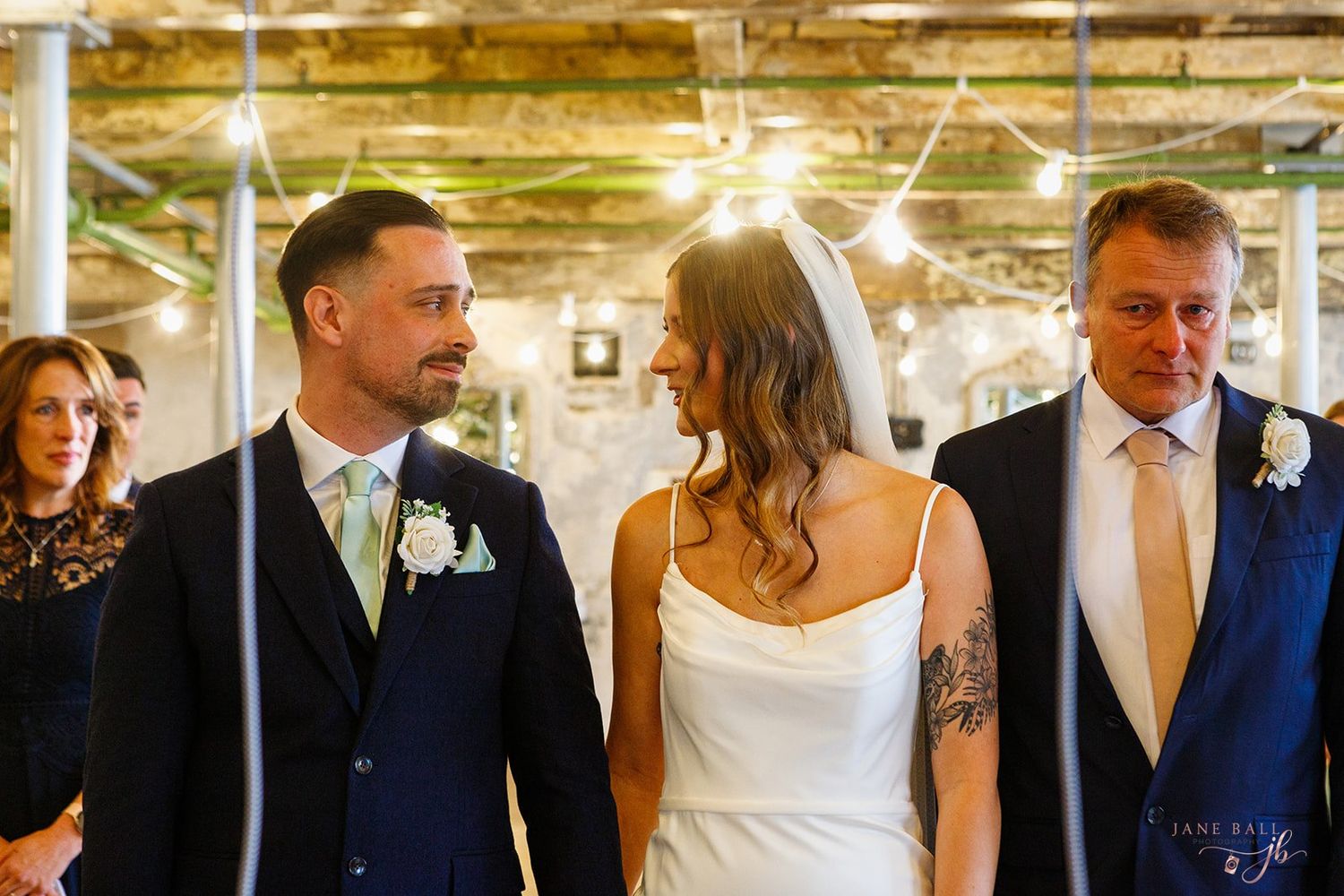 Wedding party walks together through an elegant venue hallway with decorative lighting and golden tones.
