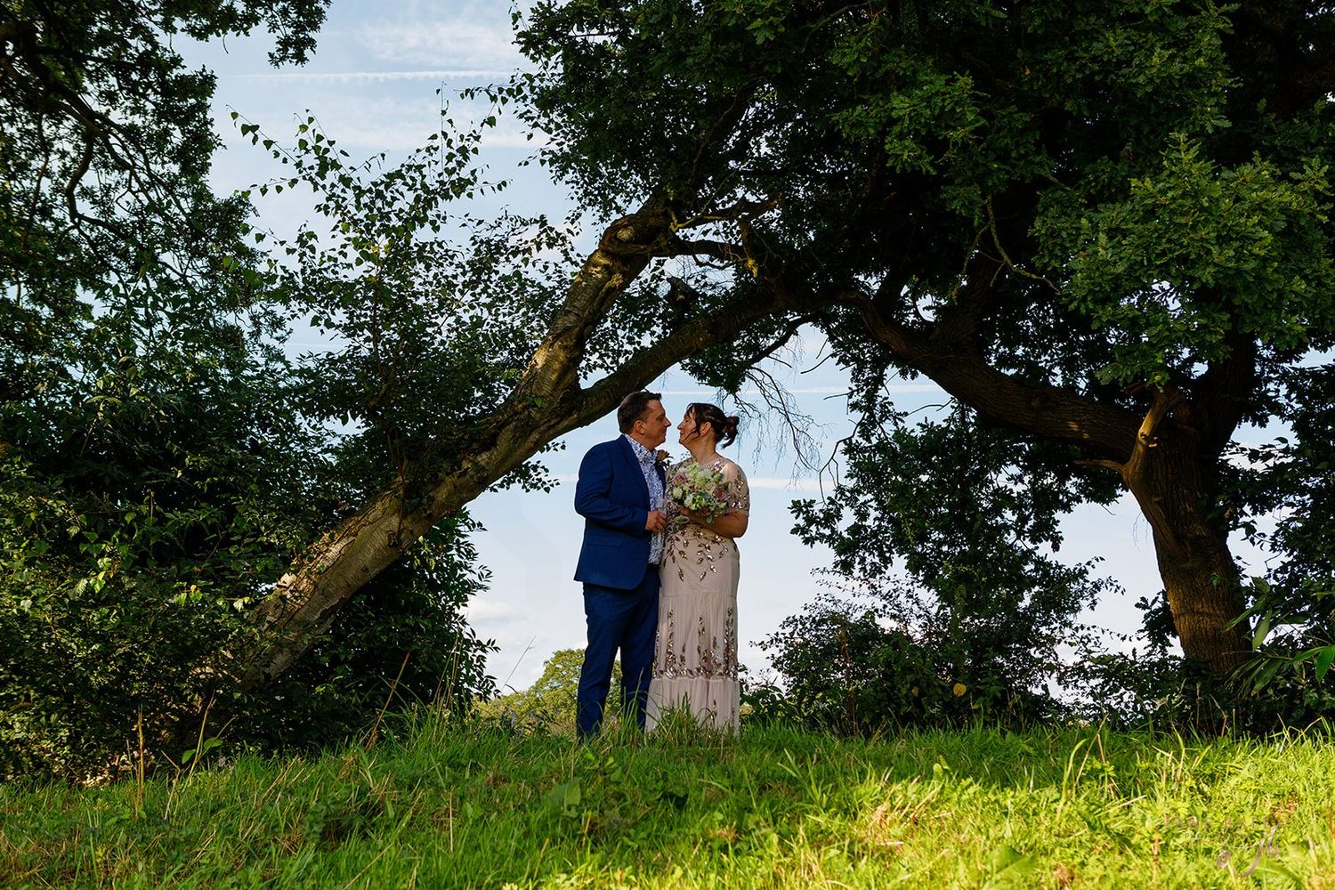 A couple stands beneath a tree during a romantic outdoor photo session at The Love Shack, Knutsford