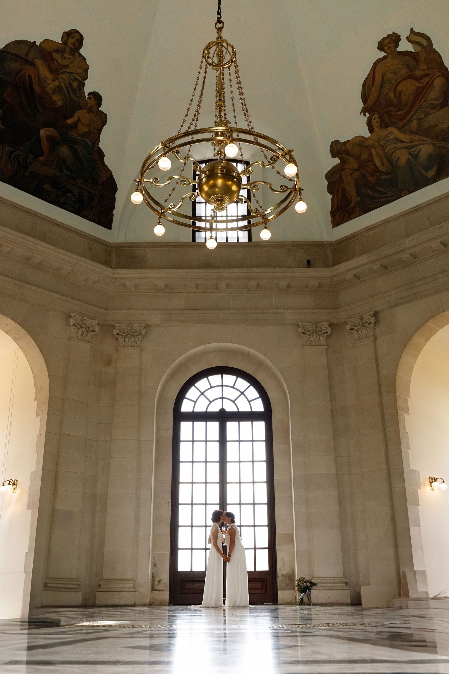 Grand ornate white marble ballroom interior with chandelier and arched windows showcasing classical architectural details.