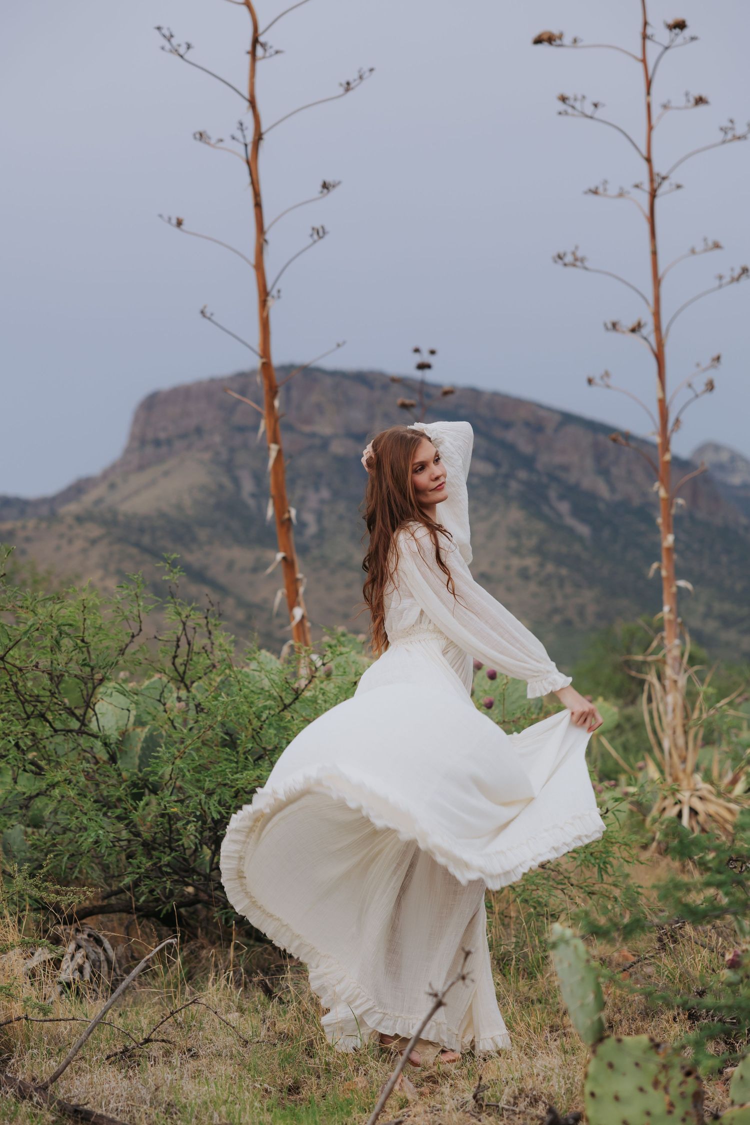 A white dress twirls dramatically against a desert landscape with mountains and cacti.