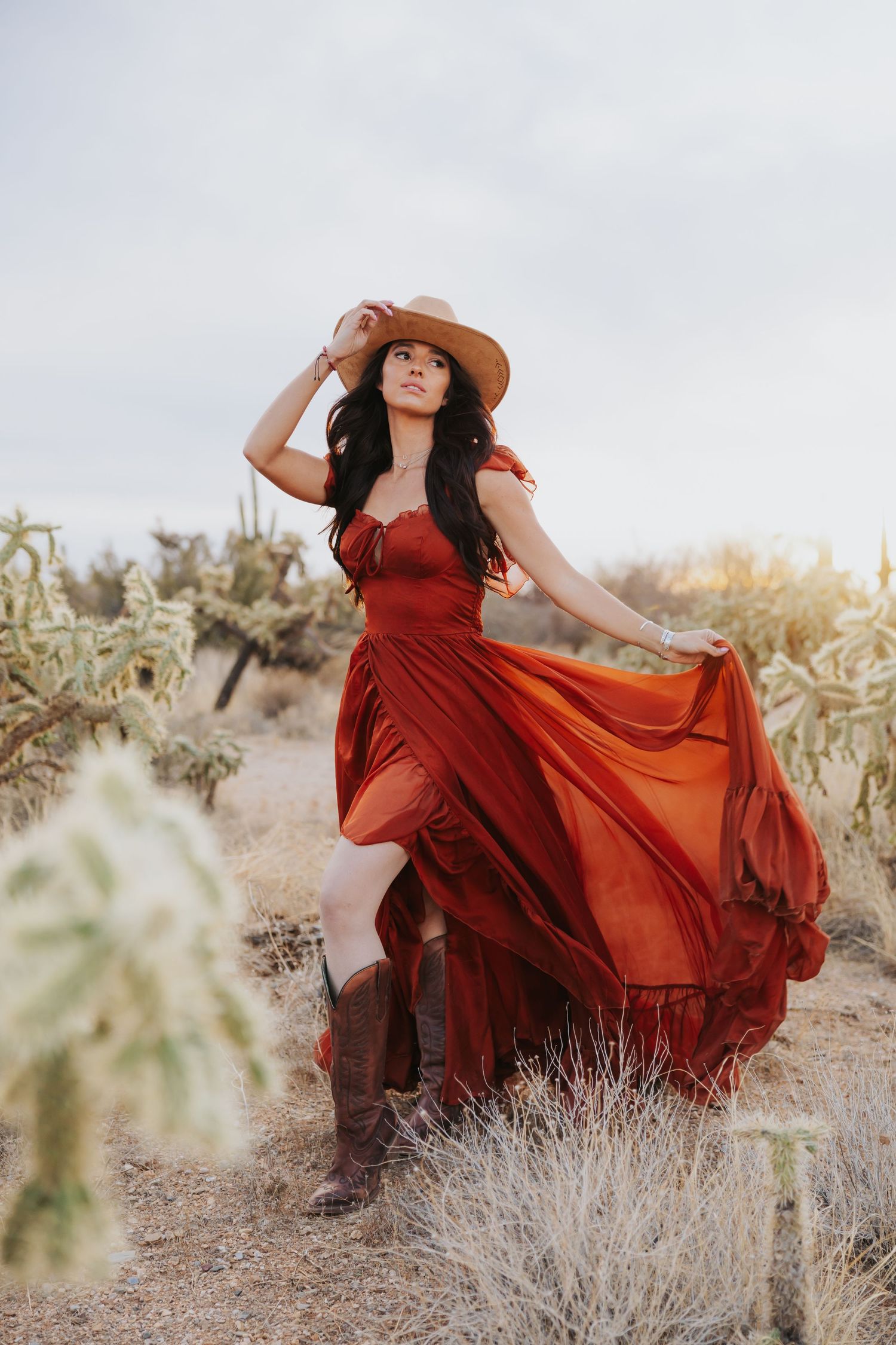 Fashion photography featuring a red dress and wide-brim hat among desert brush and cacti.