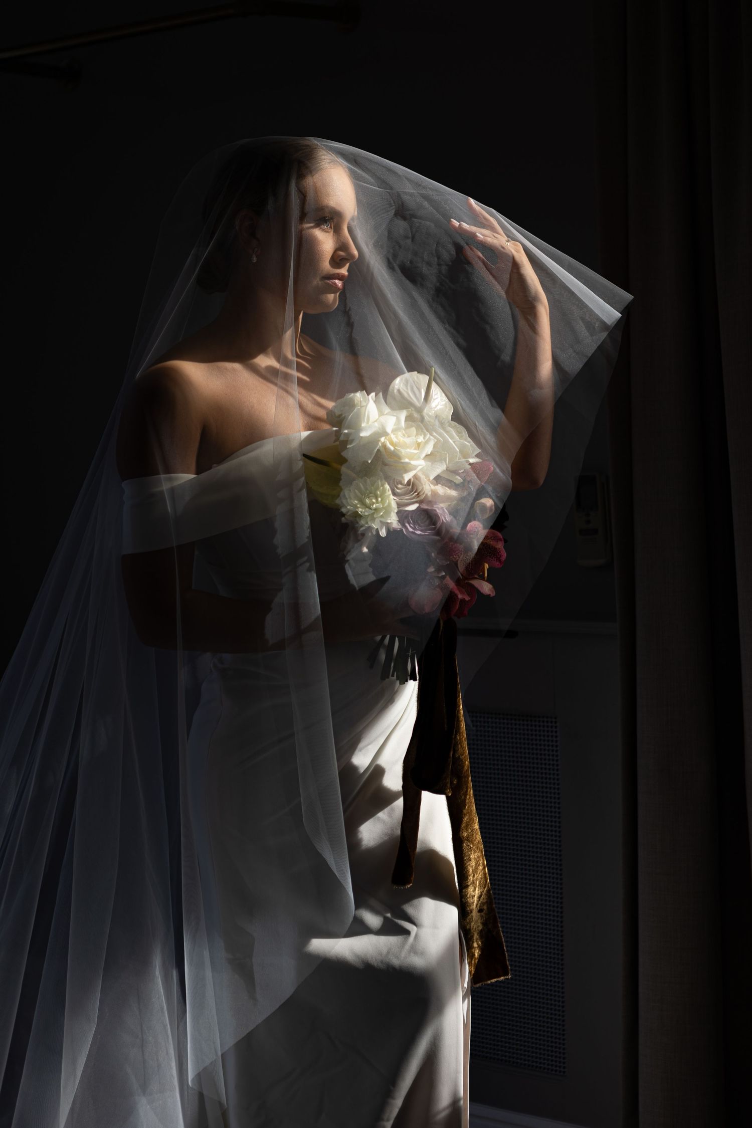 dark exposure image of bridr during bridal portraits under her veil with bridal flowers