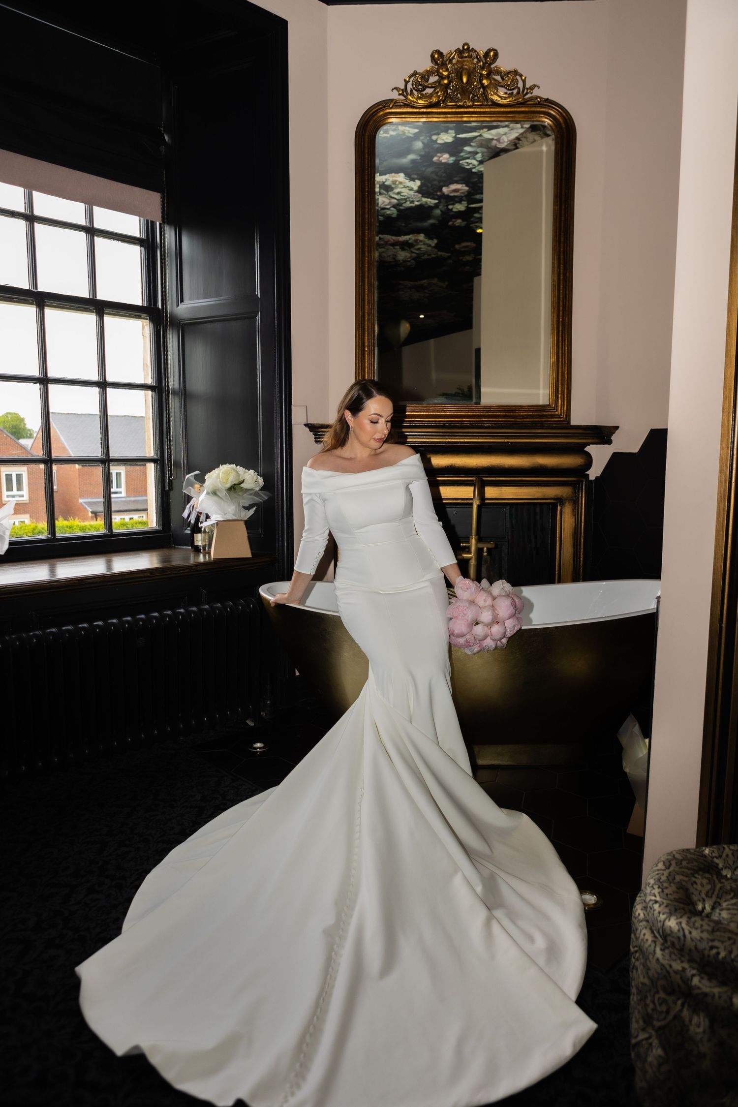 full length wedding dress shot of bride sat on the edge of the bath at Acklam Hall in the bridal suite