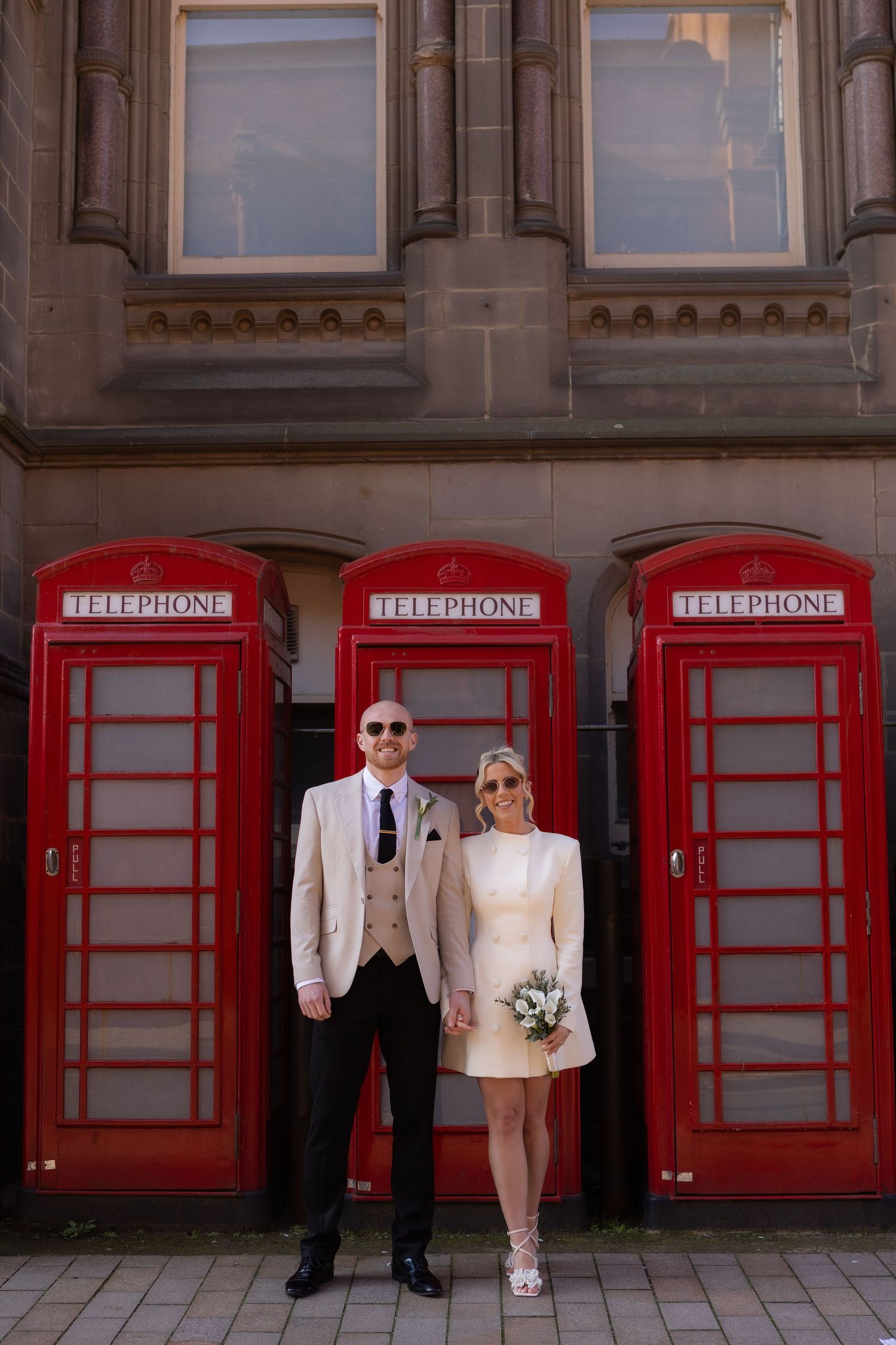 bride and groom posing infront of red postboxes with sunglasses on to create editorial style image at Middlesbrough registry office venue