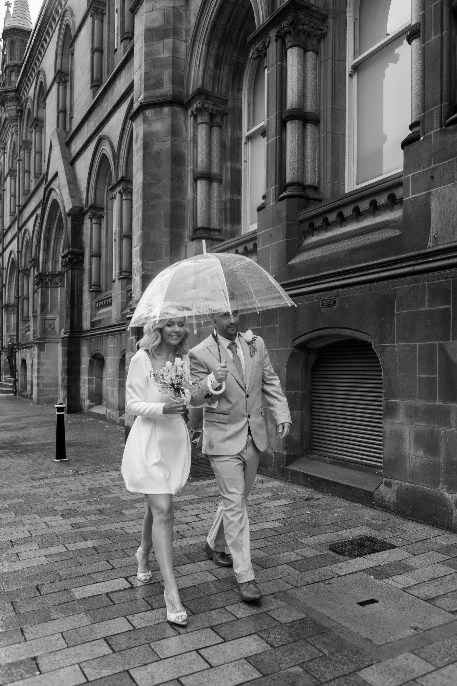 bride and groom walking out of their ceremony under umbrella