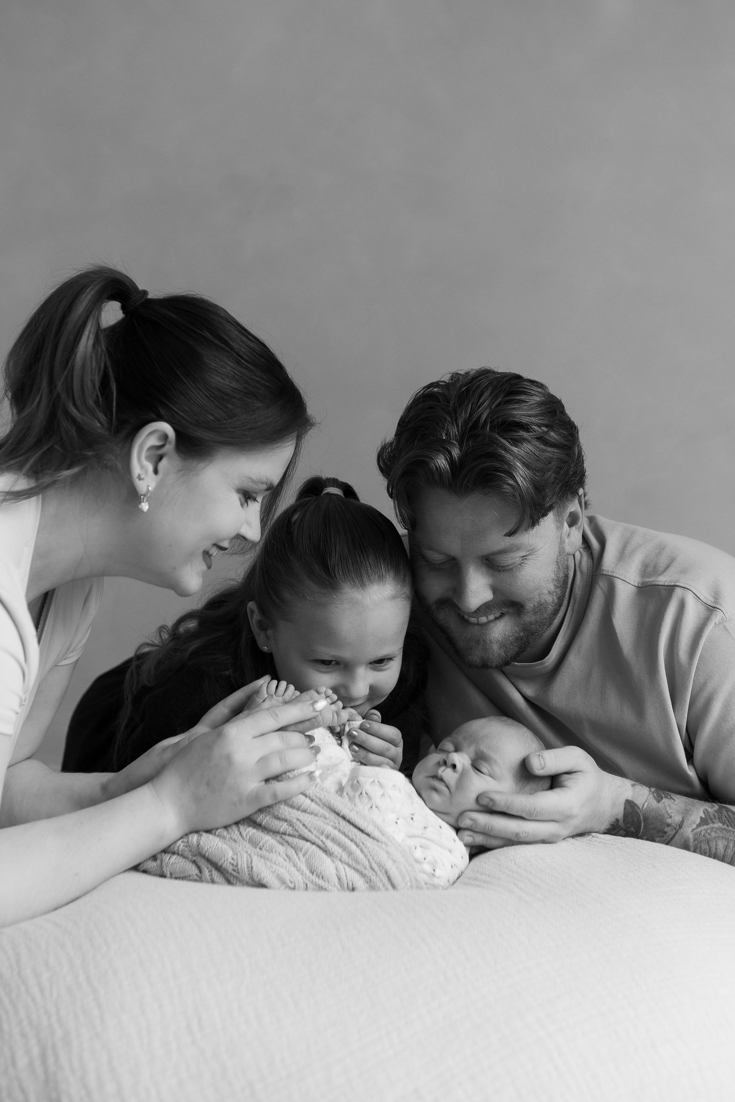 family cuddling newborn baby durning their newborn session based in Teeside studio