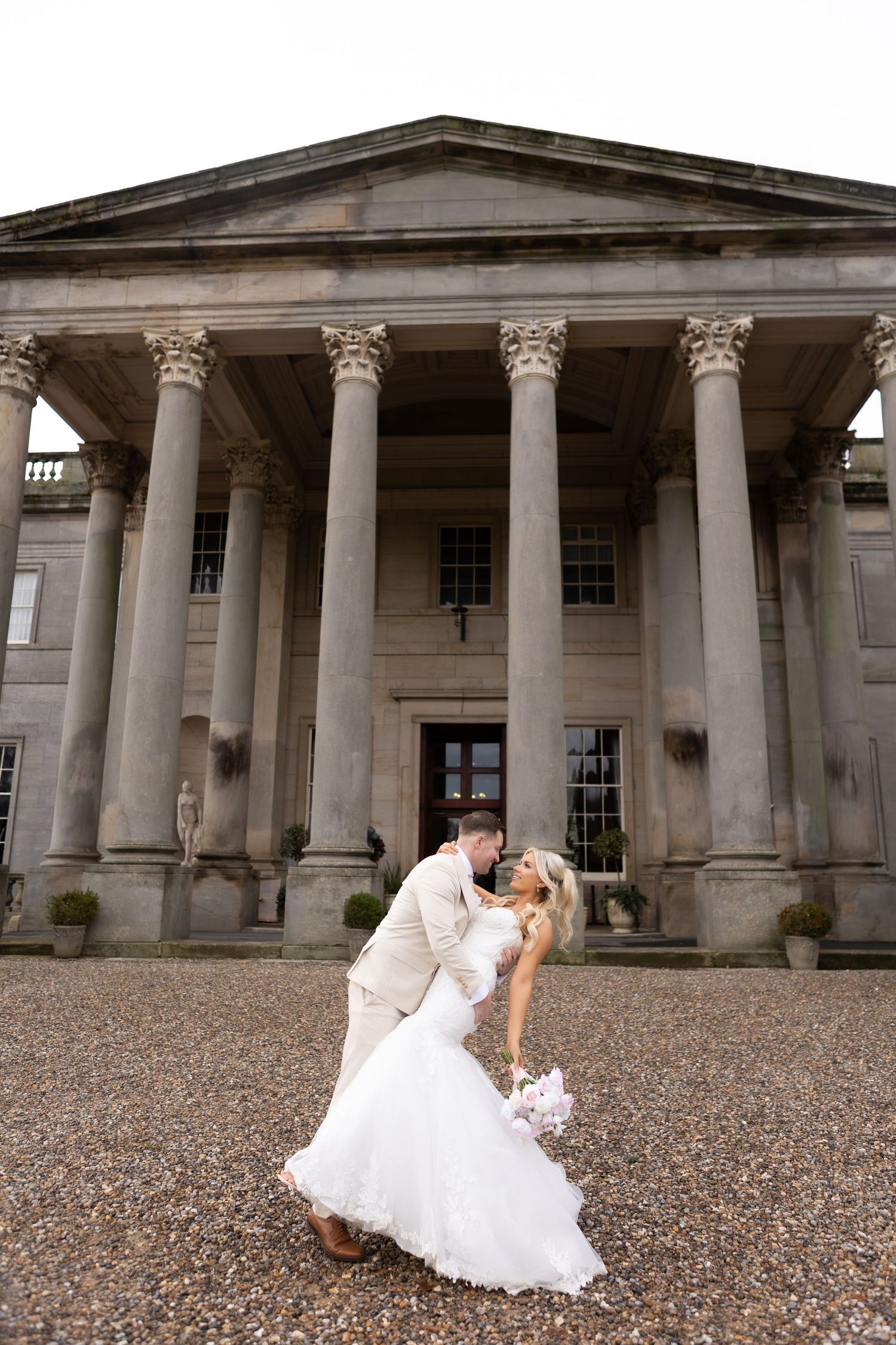 bride and groom doing a dip kiss inform of large pillars at the grounds of Wynyard hall wedding venue based in Teeside