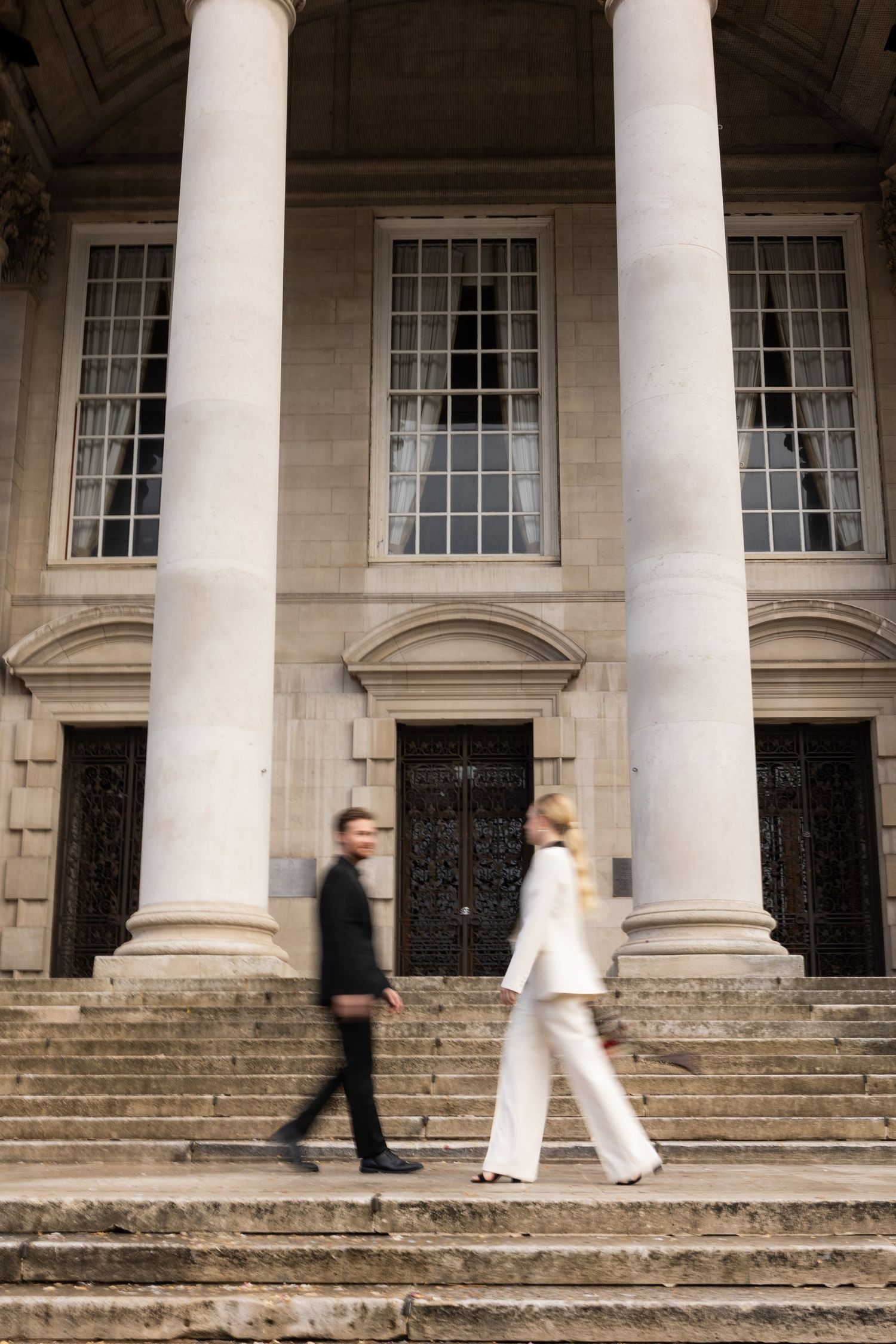 blured vogue/vanity fair style image of bride and groom walking past each other outside Leeds civic hall on the stairs