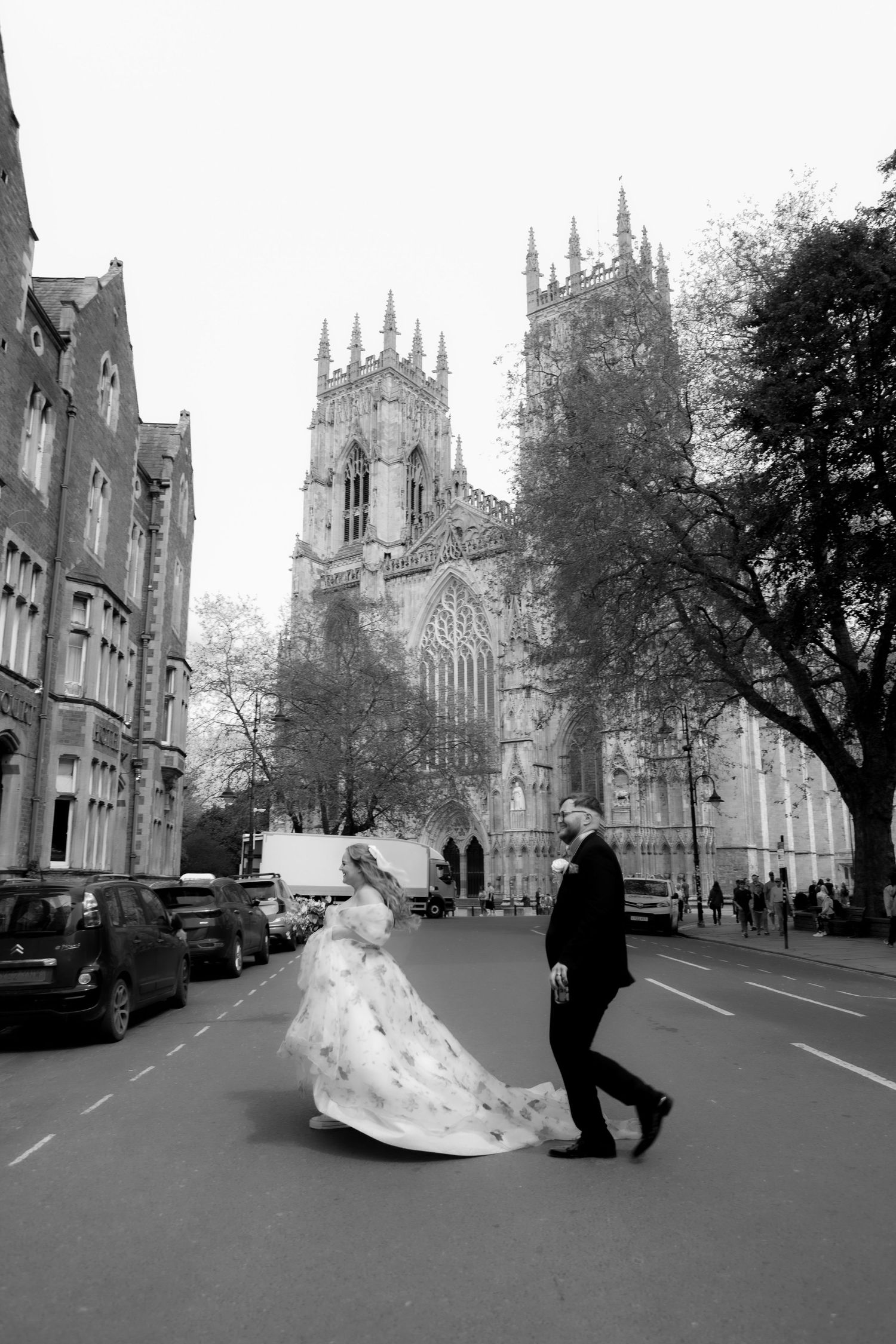 bride and groom running across the road in front of York minster on their wedding day