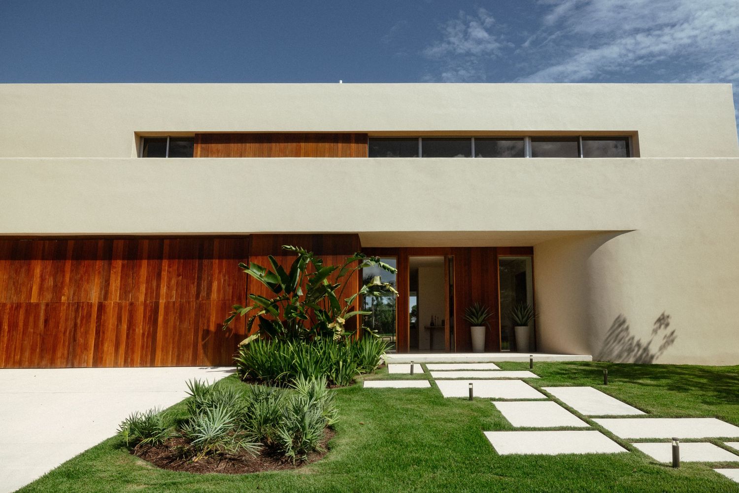 Architecture and design photography of a modern luxury home featuring minimalist architecture, warm wood detailing, and lush landscaping.
