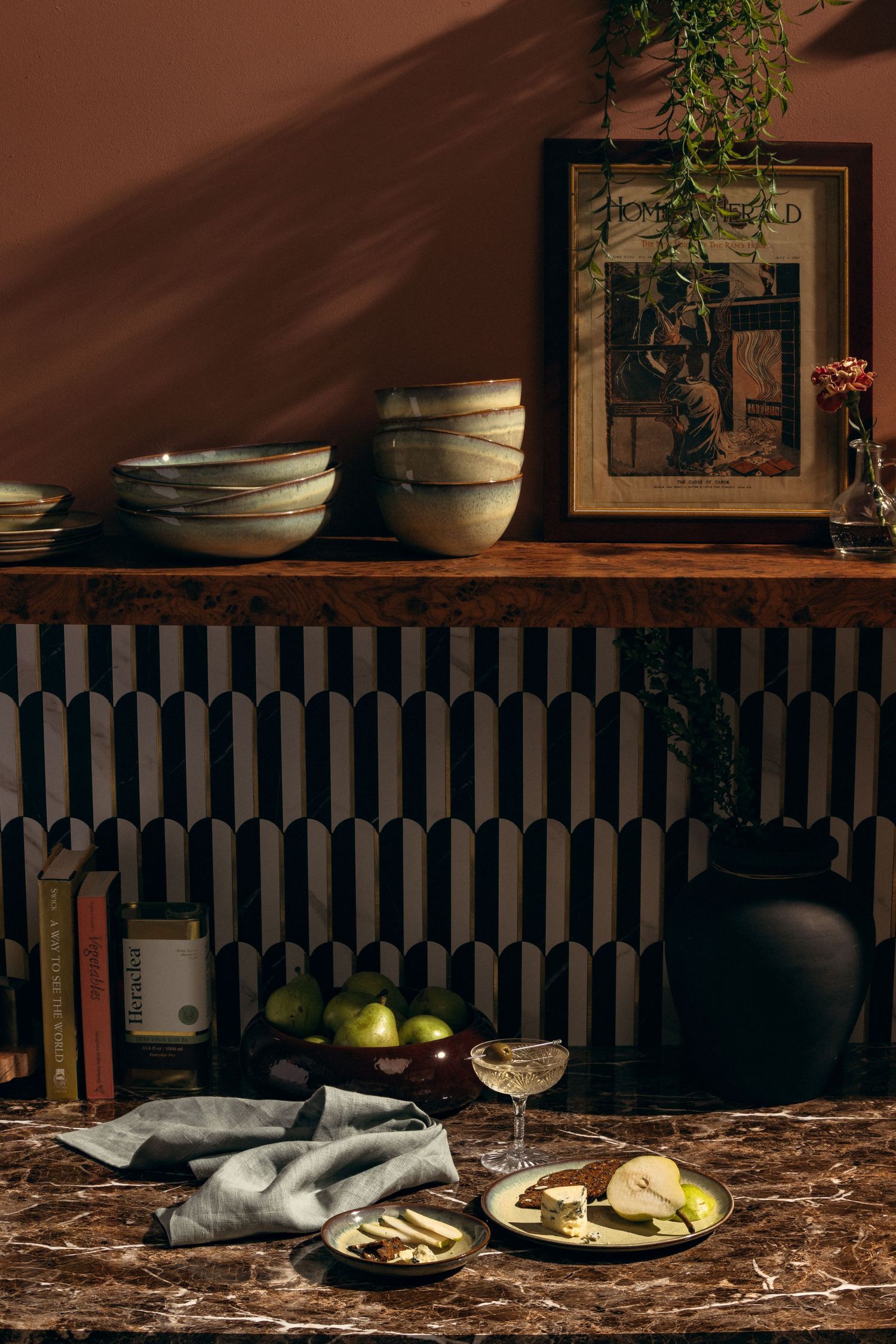 Styled product photography of handcrafted ceramic dinnerware in a curated kitchen with marble countertops and warm light.