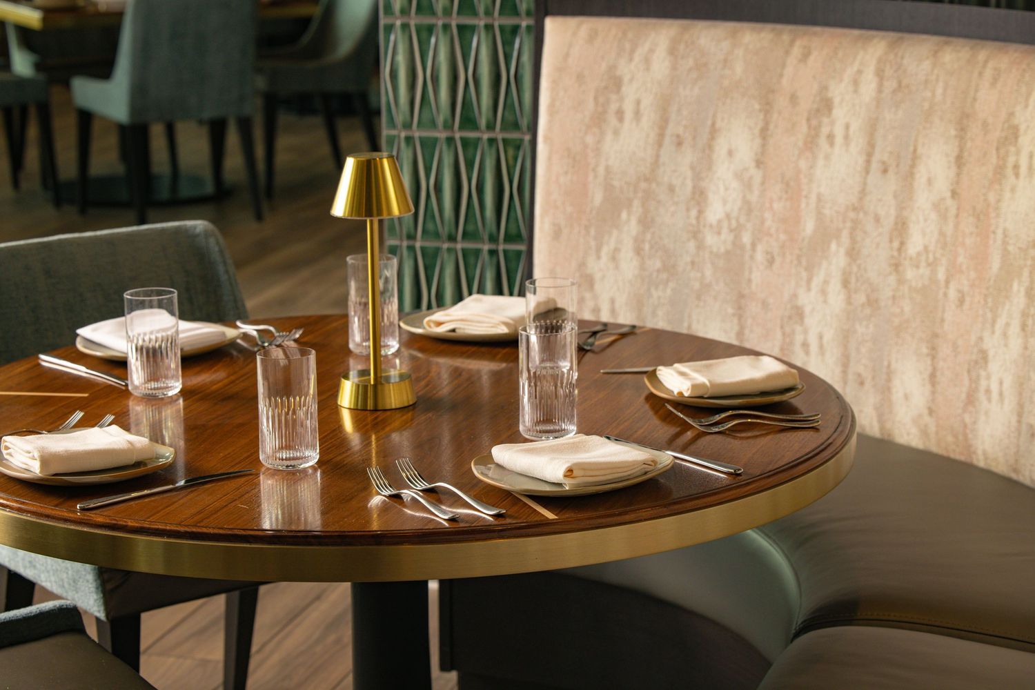 Elegant restaurant table setup with gold lamp, wood finish, and plush seating—captured for upscale interior design photography.