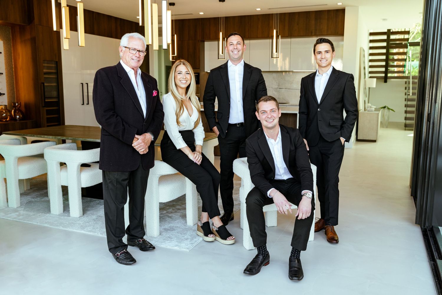 Group portrait photography of a real estate team in a contemporary luxury interior, showcasing professional branding and modern design.