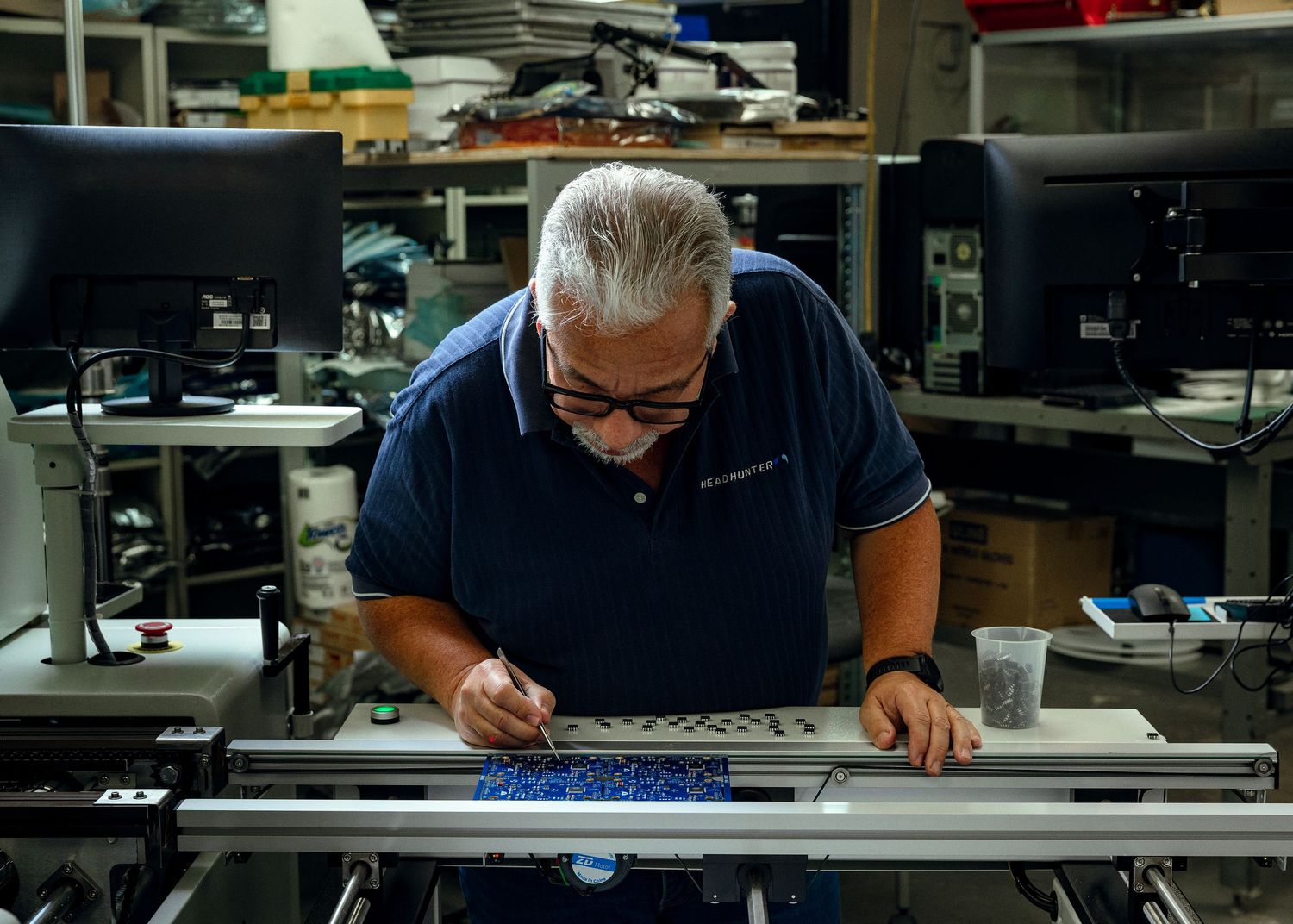 Lifestyle photography of an electronics technician inspecting circuit boards in a precision manufacturing facility.