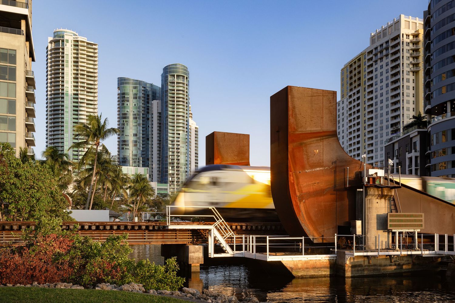 Downtown skyline with modern towers and moving train, showcasing urban design and transportation architecture photography.
