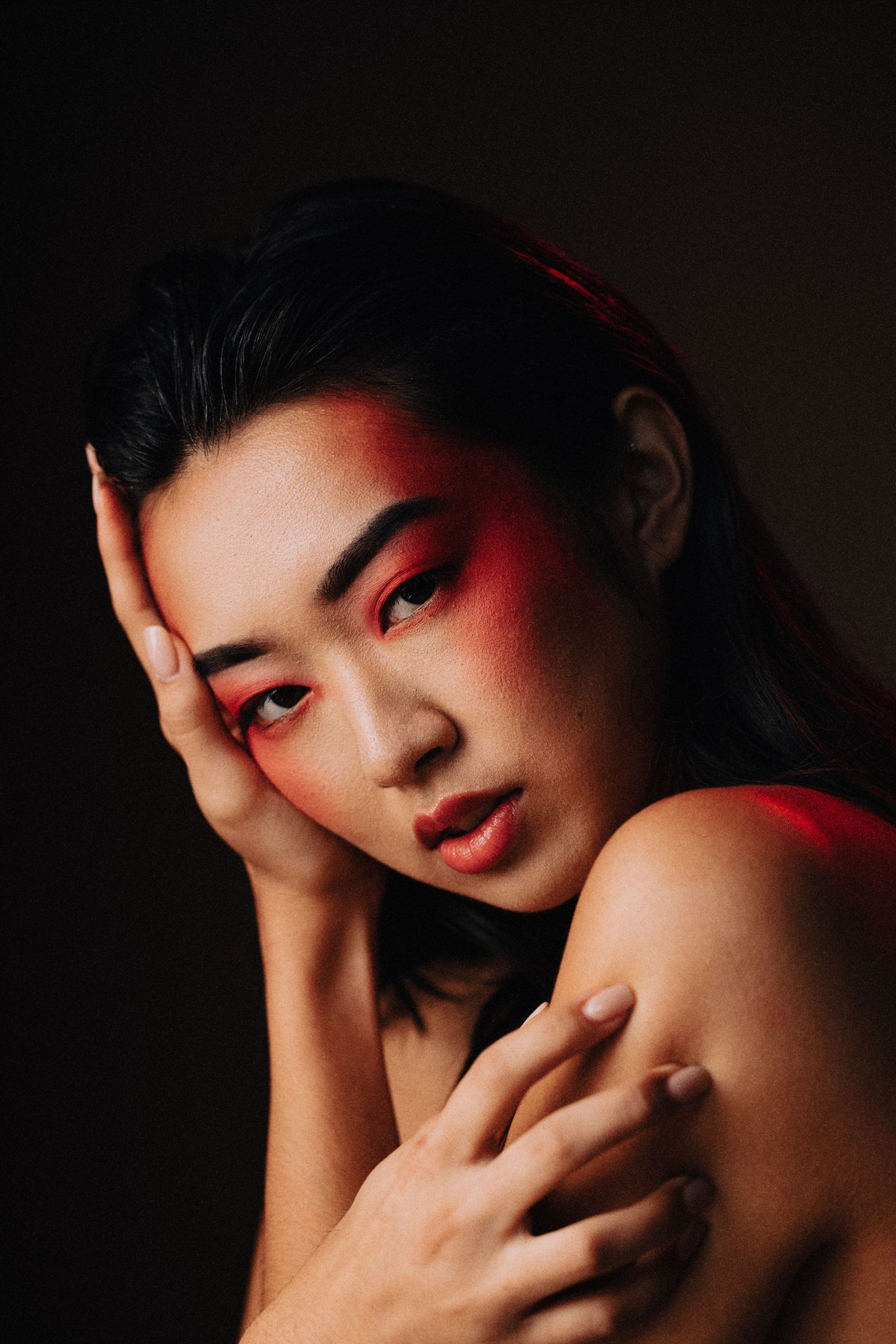 Beauty photograph of female model wearing edgy make up posing in a photo studio with a black backdrop shot by commercial photographer