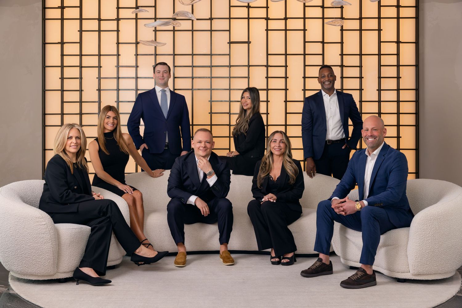 Professional group portrait photography of a corporate leadership team posed in a modern office lounge with architectural backdrop.