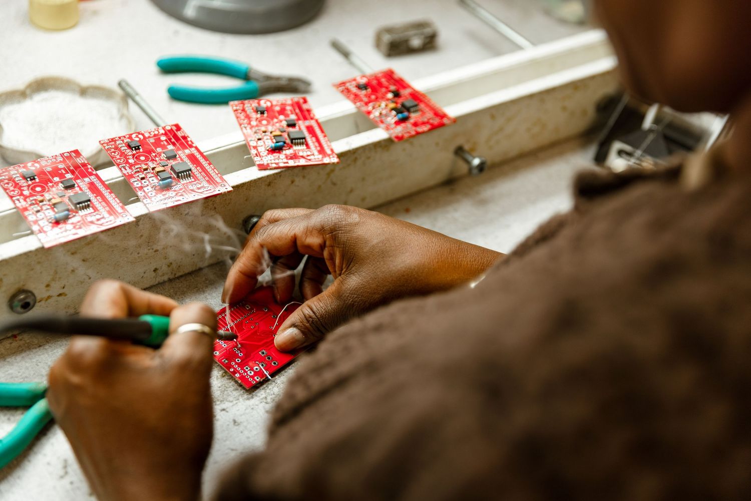 Corporate business photography of an electronics technician assembling circuit boards, showcasing precision manufacturing expertise.