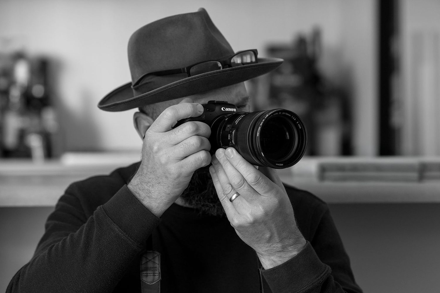 A black and white Image of Jason Robins wearing his Akubra Hat, a Professional photographer taking a photo with a Canon DSLR camera.