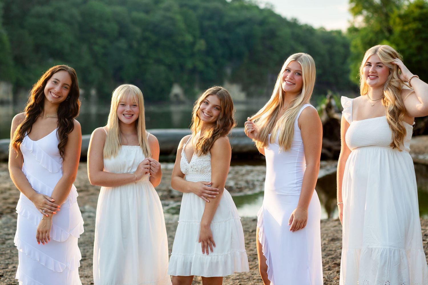 A group high school senior girls wearing white dresses stand together in a line outdoors at Palisades-Kepeler Park near Mt. Vernon Iowa.