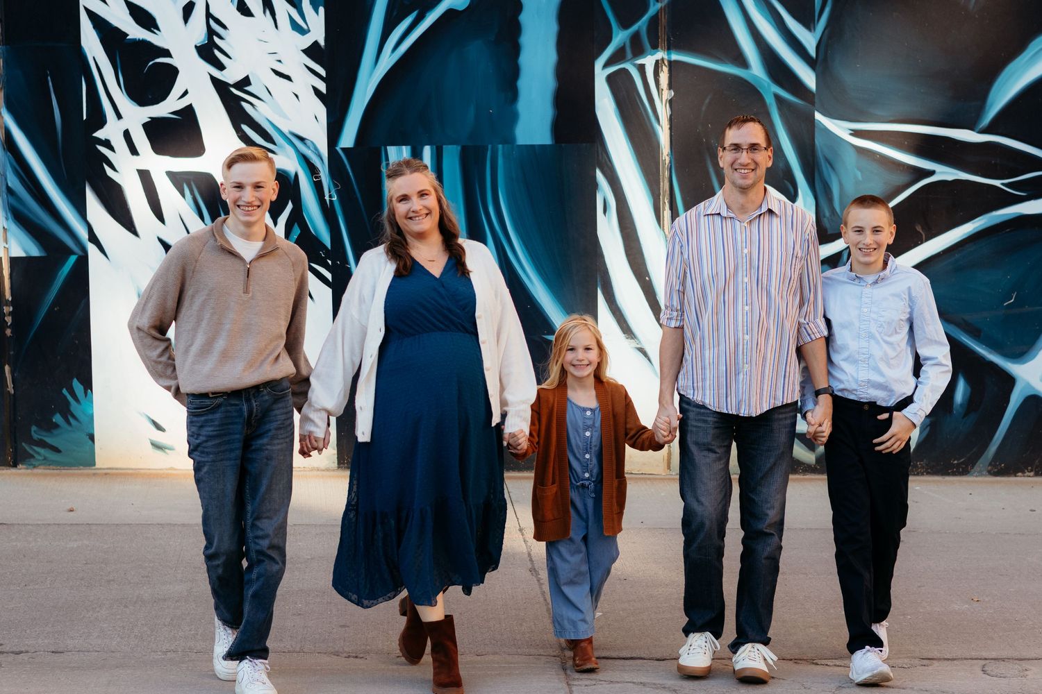 Marion photographer Nichole Sieck walks with her family in front of an Iowa City Mural.