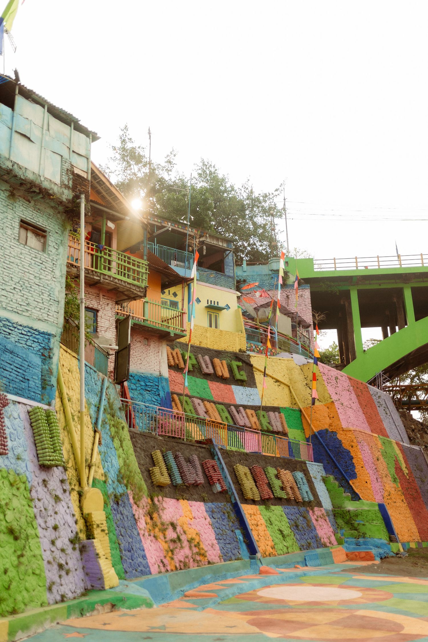 Colorful painted buildings and stairs in a vibrant urban neighborhood with rainbow murals covering walls.