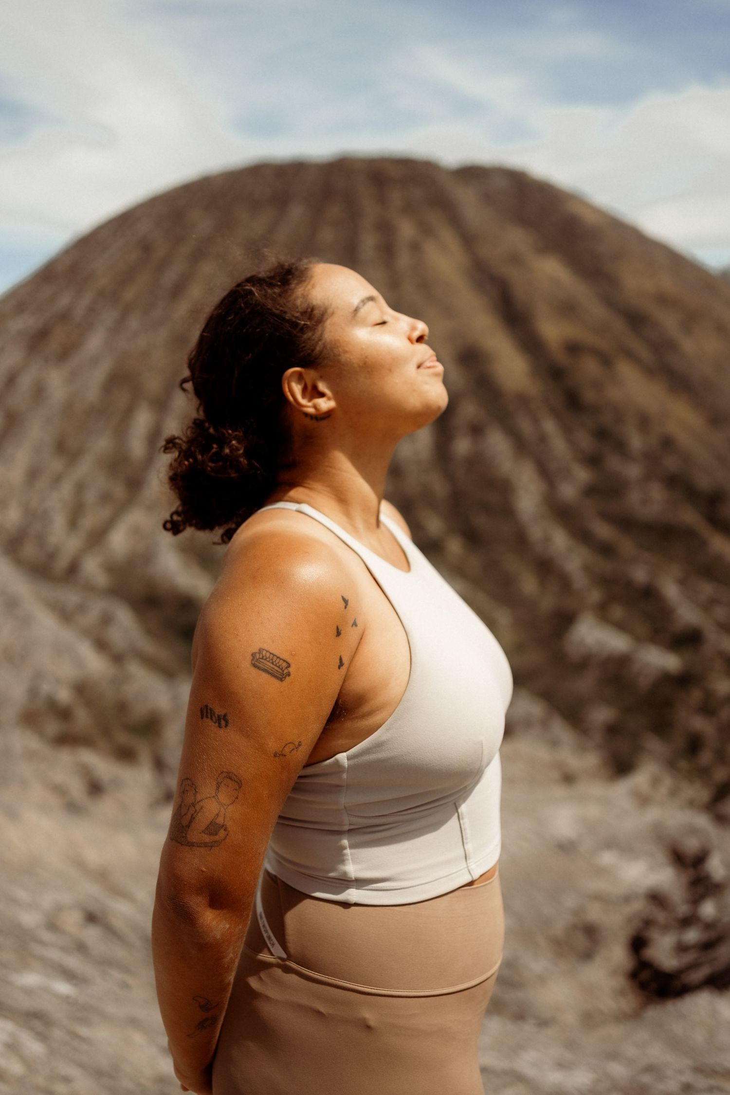 Woman in athletic wear meditating with eyes closed in front of Mount Bromo volcano, Indonesia.