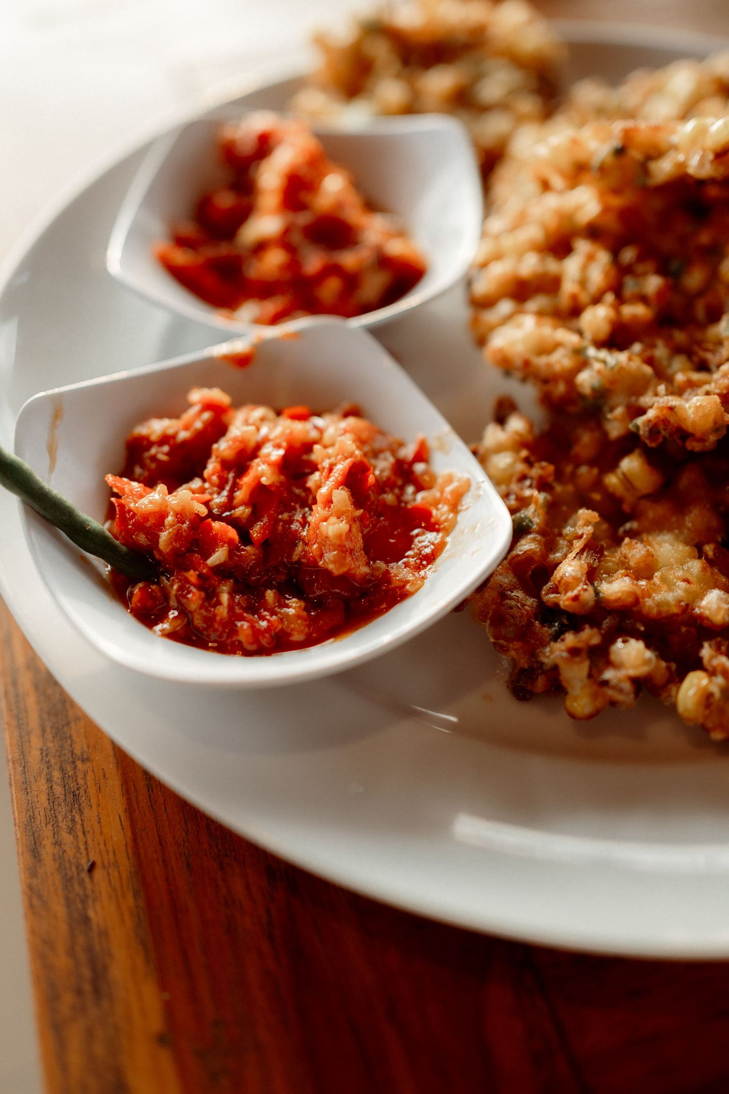 Traditional Indonesian sambal chili sauce served in white dishes alongside crispy fried rice on a plate.