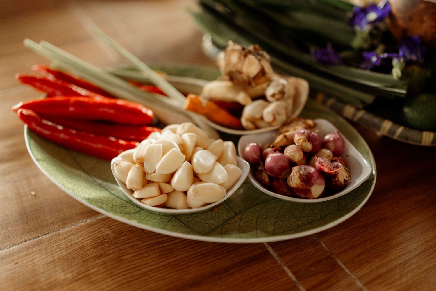 Fresh Indonesian cooking ingredients including red chilies, garlic, shallots, and lemongrass on a plate.