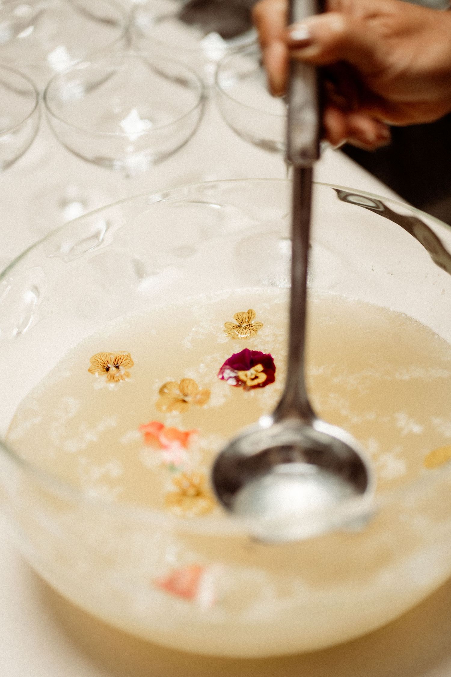 Elegant punch bowl with floral garnishes and a silver ladle, perfect for wedding receptions and special events.