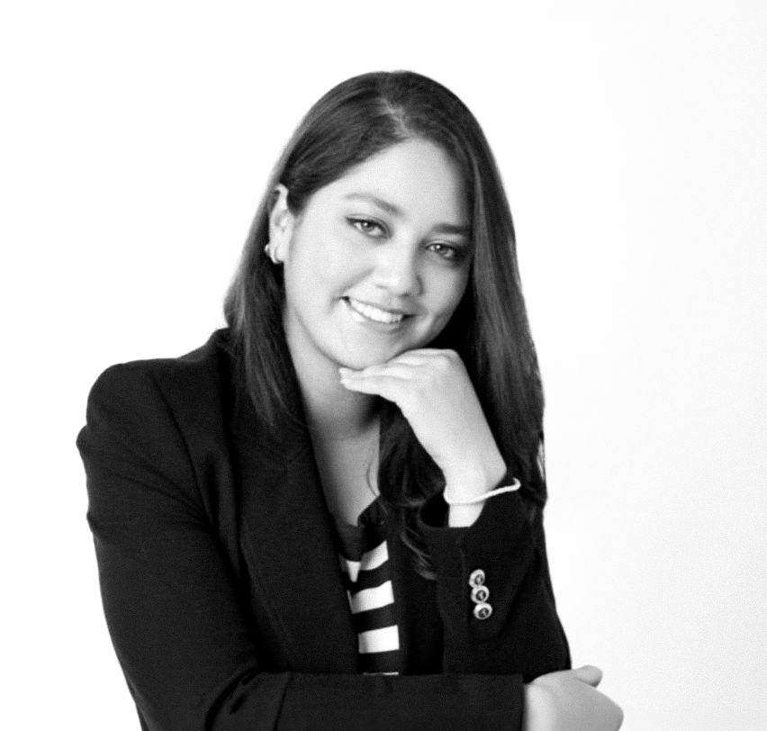 Professional woman in black blazer posing confidently with hand on chin, black and white portrait photo.