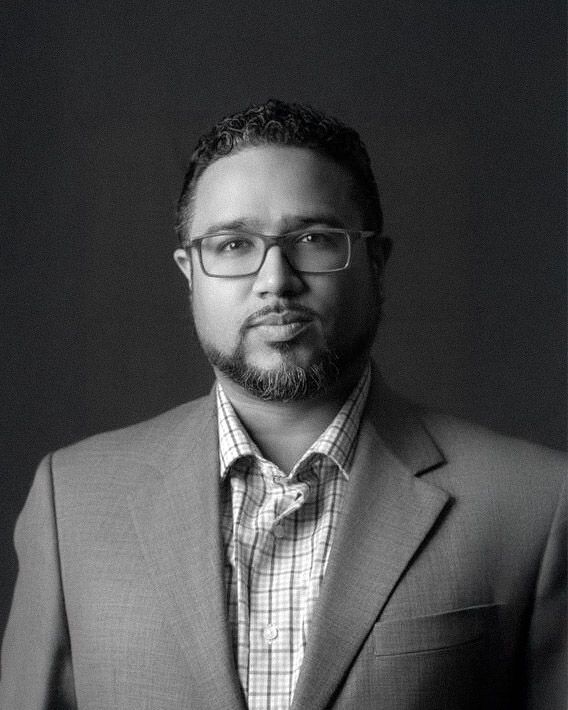 Black and white professional headshot series showing a person in glasses and business attire from different angles.
