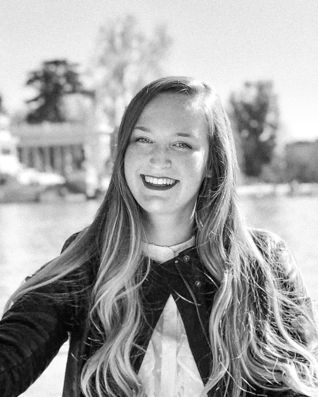 Black and white portrait series showing a person with long wavy hair laughing and smiling naturally outdoors.