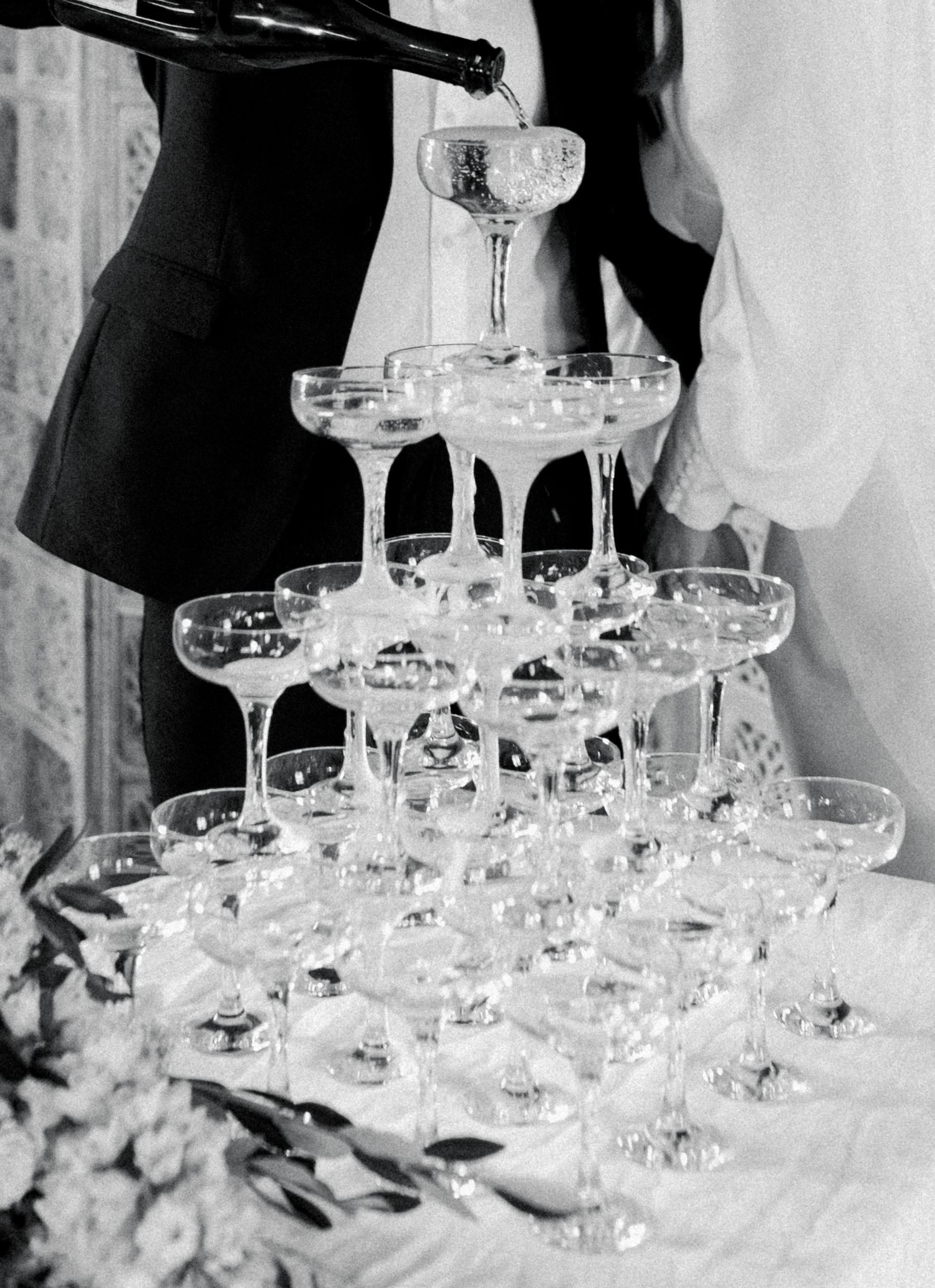 Elegant champagne coupe glasses arranged in rows on a white tablecloth at a formal event.
