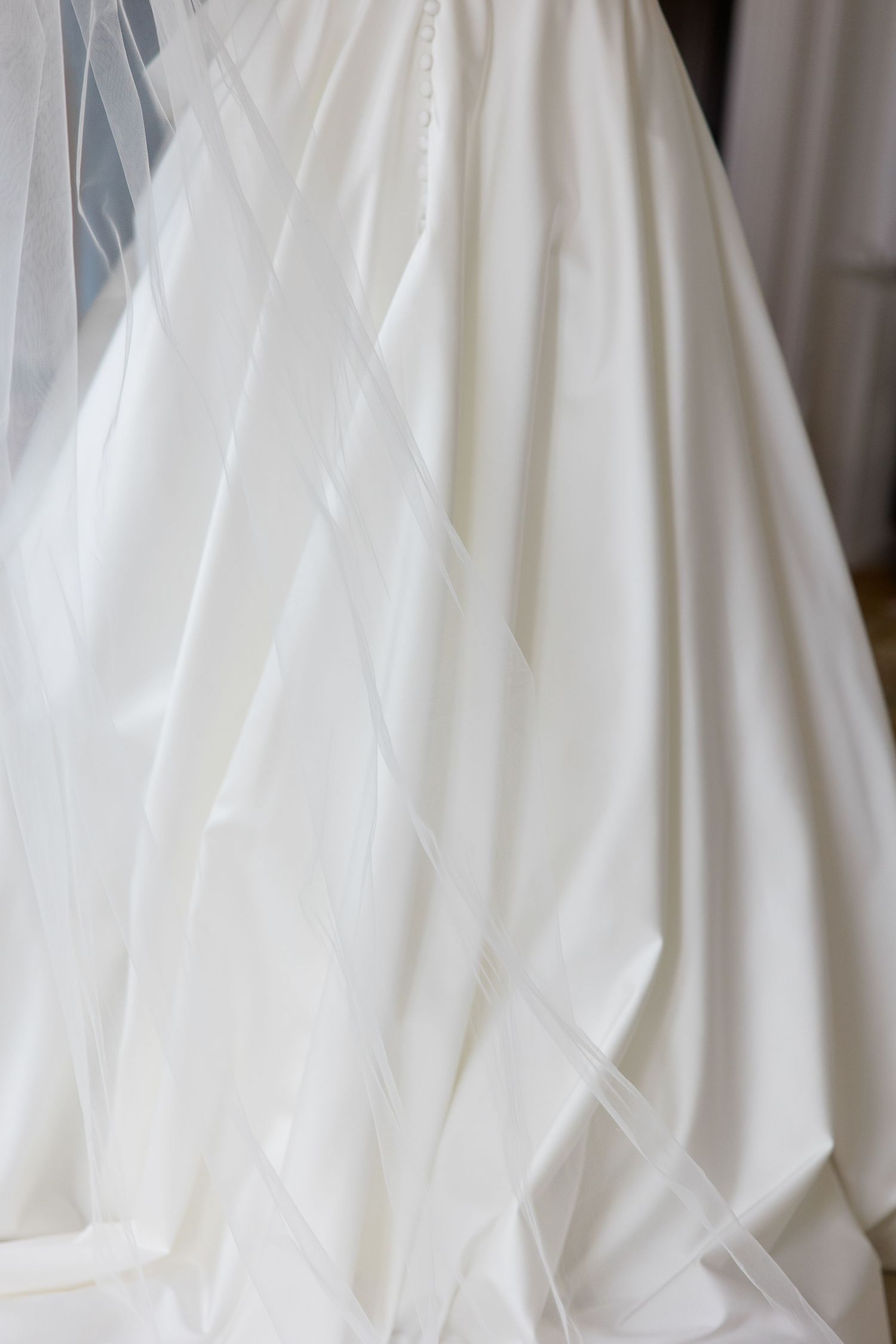 Close-up view of white wedding dress fabric showing delicate folds and draping details.