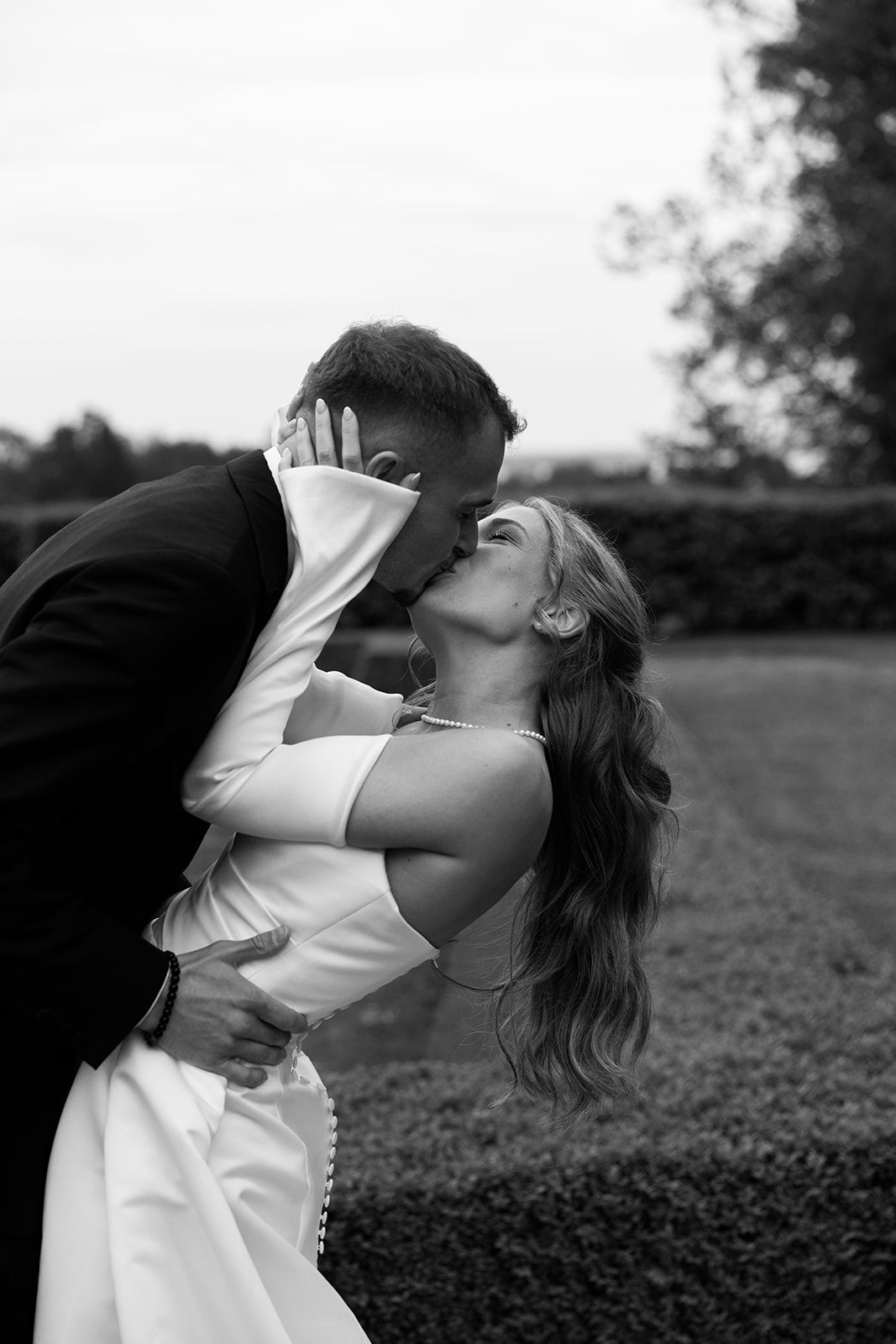 A black and white photo series shows a person in a white dress moving expressively in an outdoor field.