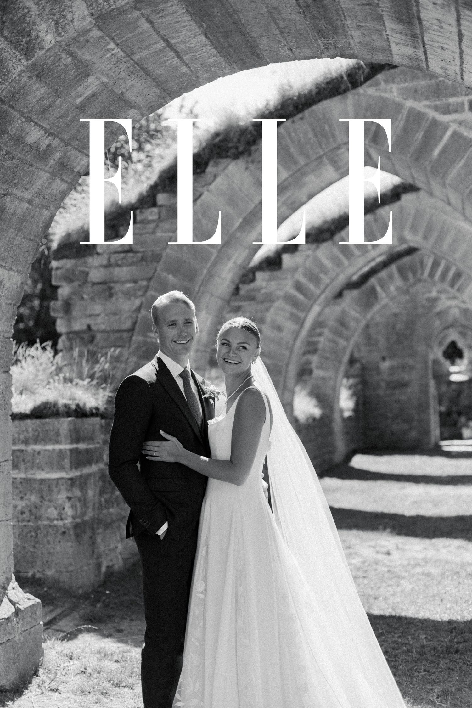 Black and white wedding portraits captured under historic stone archways.