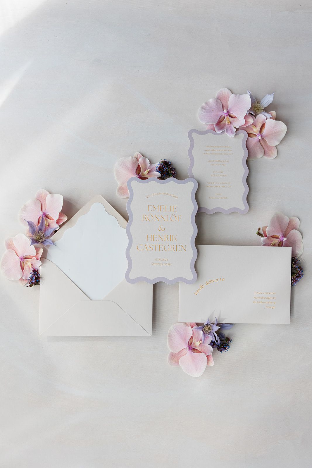 Elegant white wedding invitation cards with delicate pink floral accents arranged in a minimalist flat lay composition.