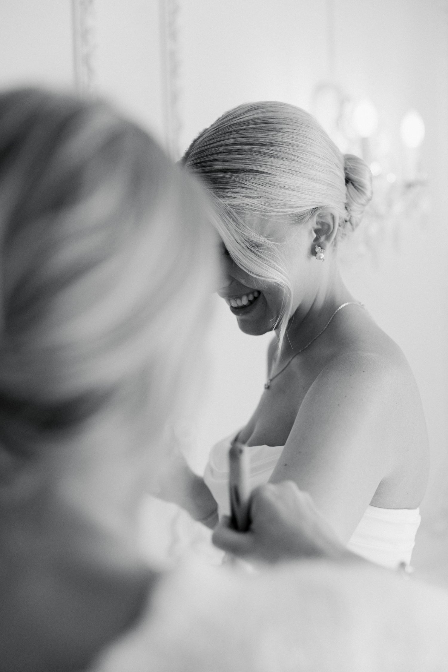 Black and white candid getting ready moment showing laughter and joy during wedding preparations.