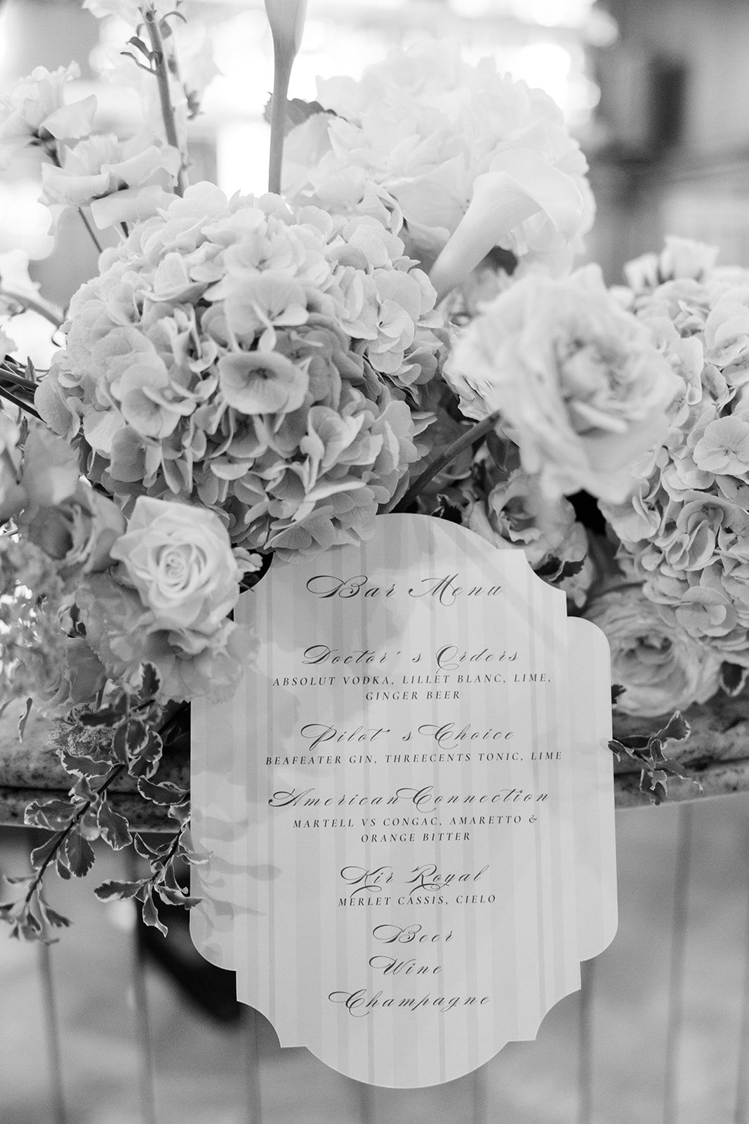 Black and white wedding stationery cards with elegant calligraphy displayed alongside floral arrangements.