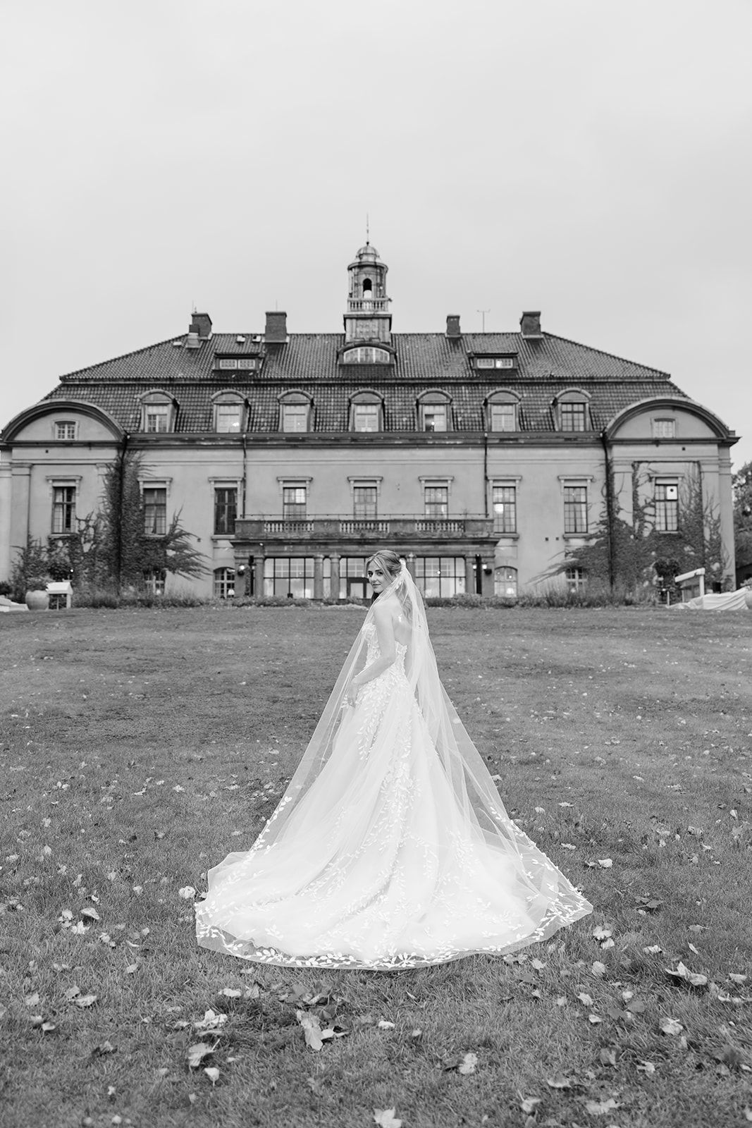 A series of black and white photographs showing a wedding dress displayed on a lawn in front of a historic mansion.
