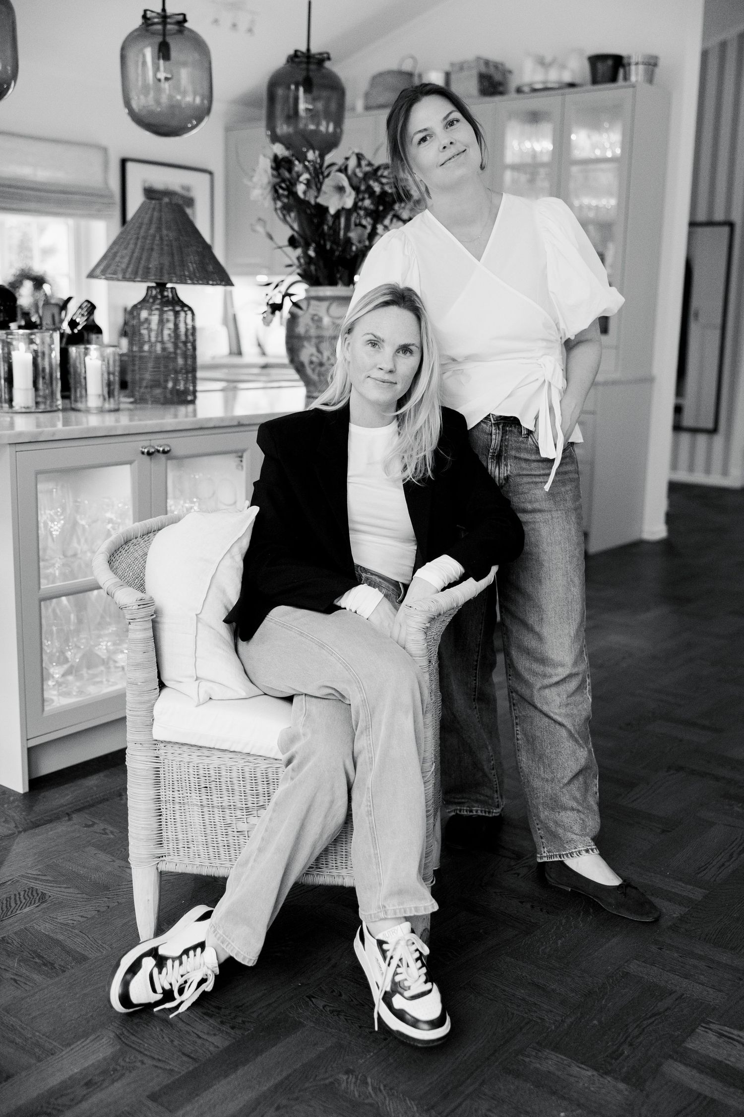 Black and white interior photo showing two people in casual attire posing together in a modern home setting.