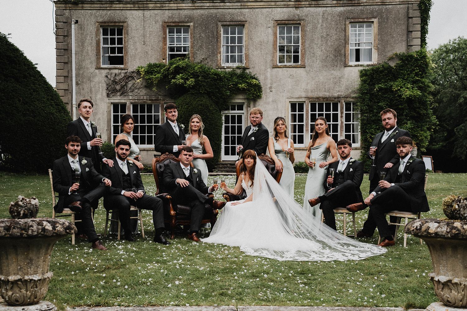 A wedding celebration unfolds outside a stately Georgian manor house with guests seated on the lawn during a summer ceremony.