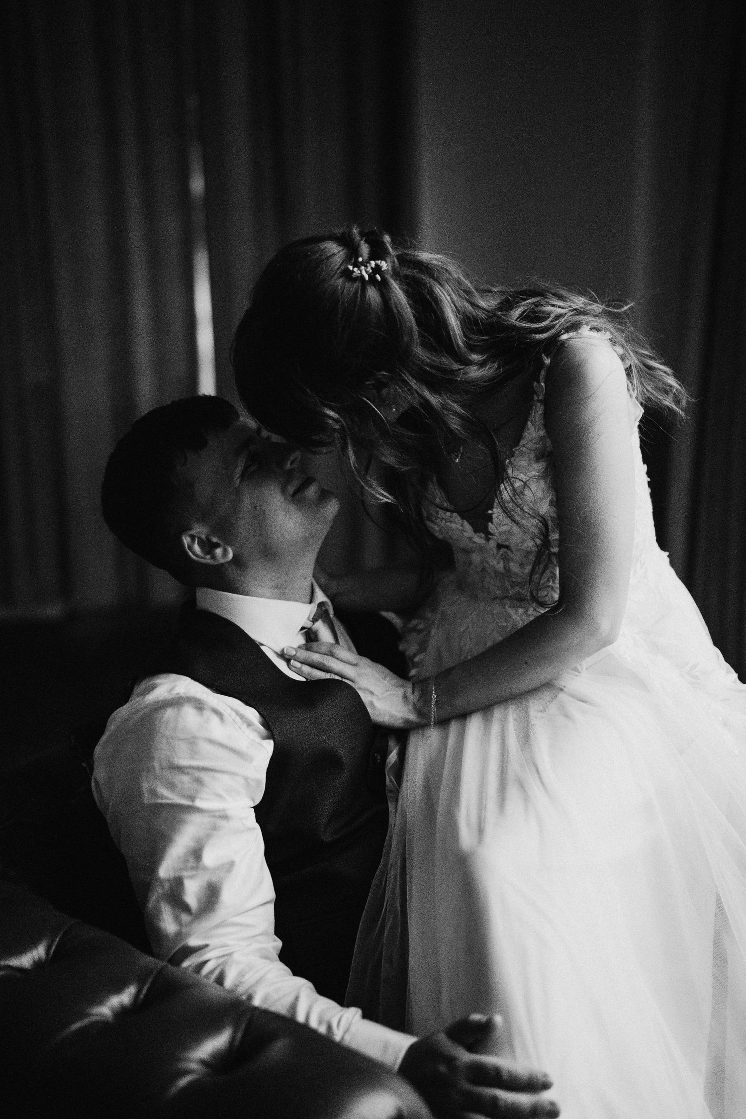 Intimate black and white wedding photo showing tender moment between newlyweds in romantic lighting.