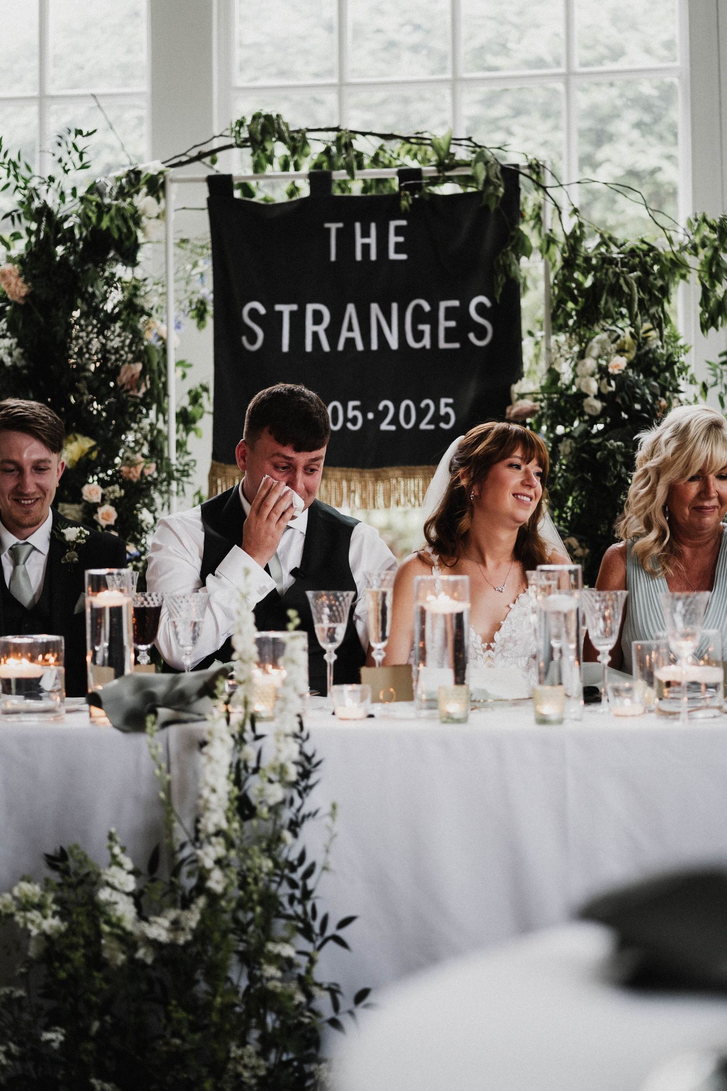 Elegant wedding reception table setting with glass panels displaying 'The Stranges 05-2023' text and floral decorations.
