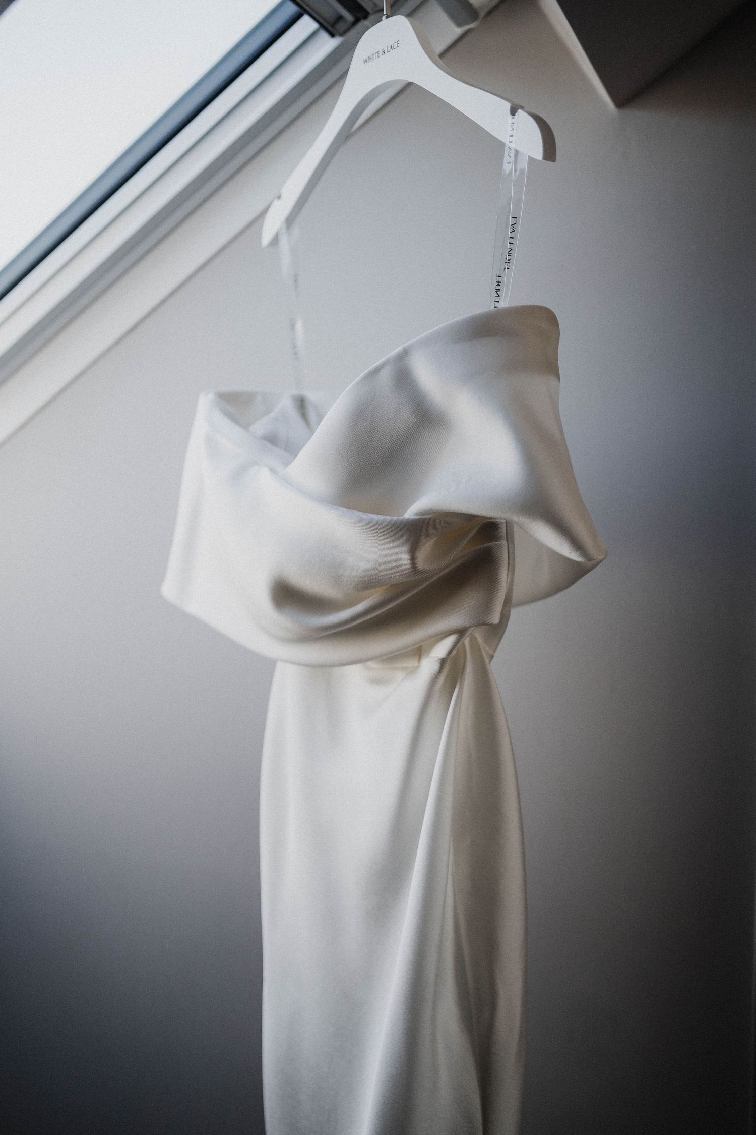 Minimalist white fabric draped elegantly over a display form against a neutral gray background.