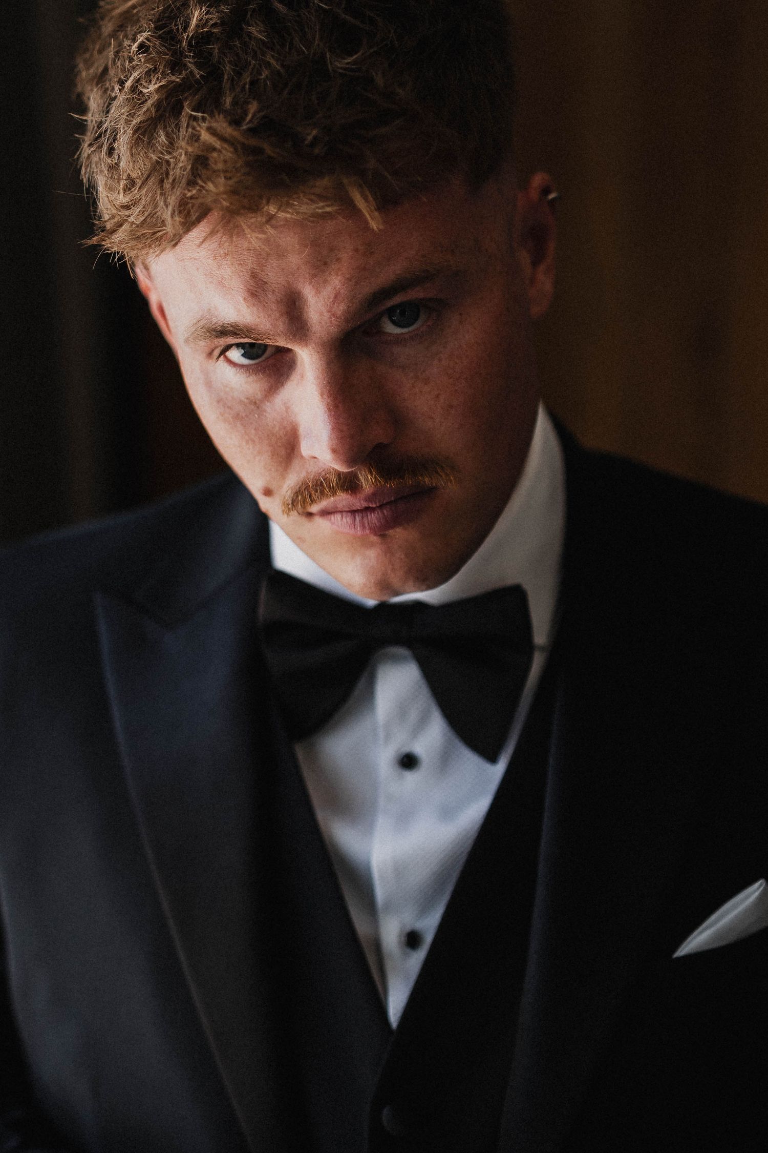 Series of dramatic portraits showing person in black tuxedo and bow tie with moody lighting.