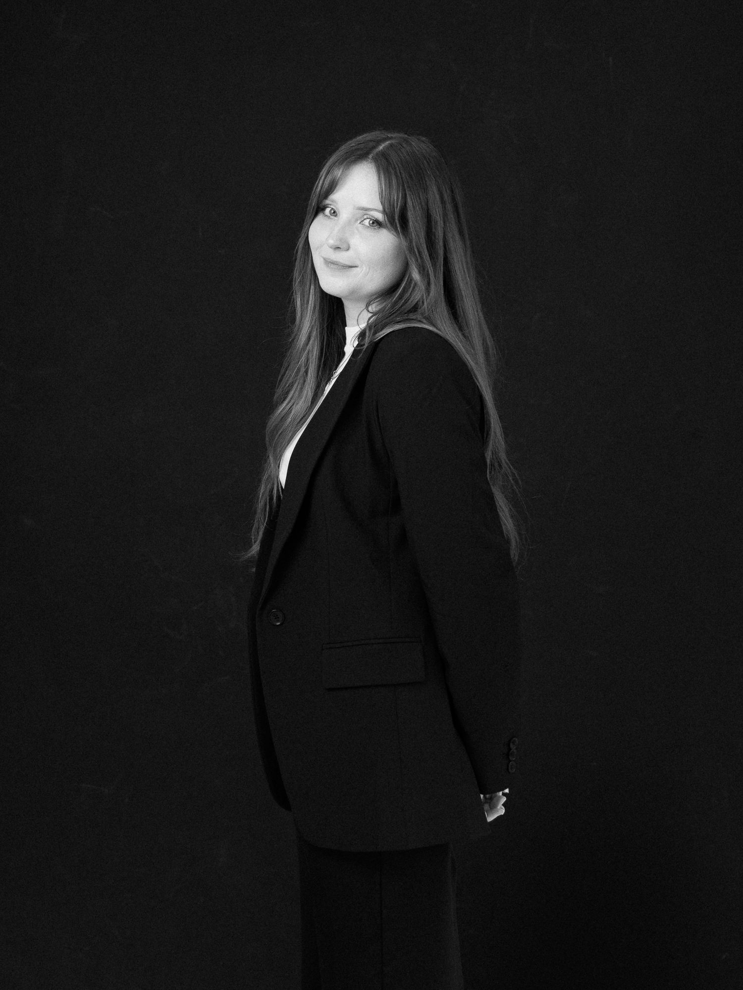 A series of black and white artistic portraits showing a figure in a black outfit against a dark background.
