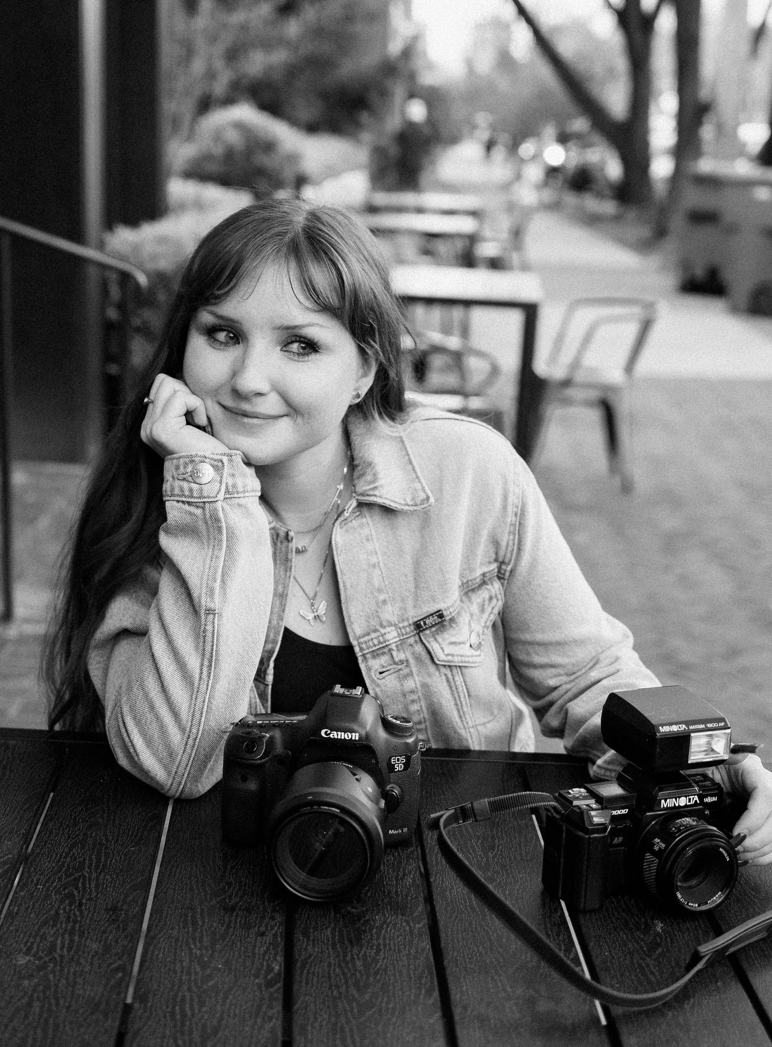 Vintage style portrait of photographer with cameras at outdoor cafe table.