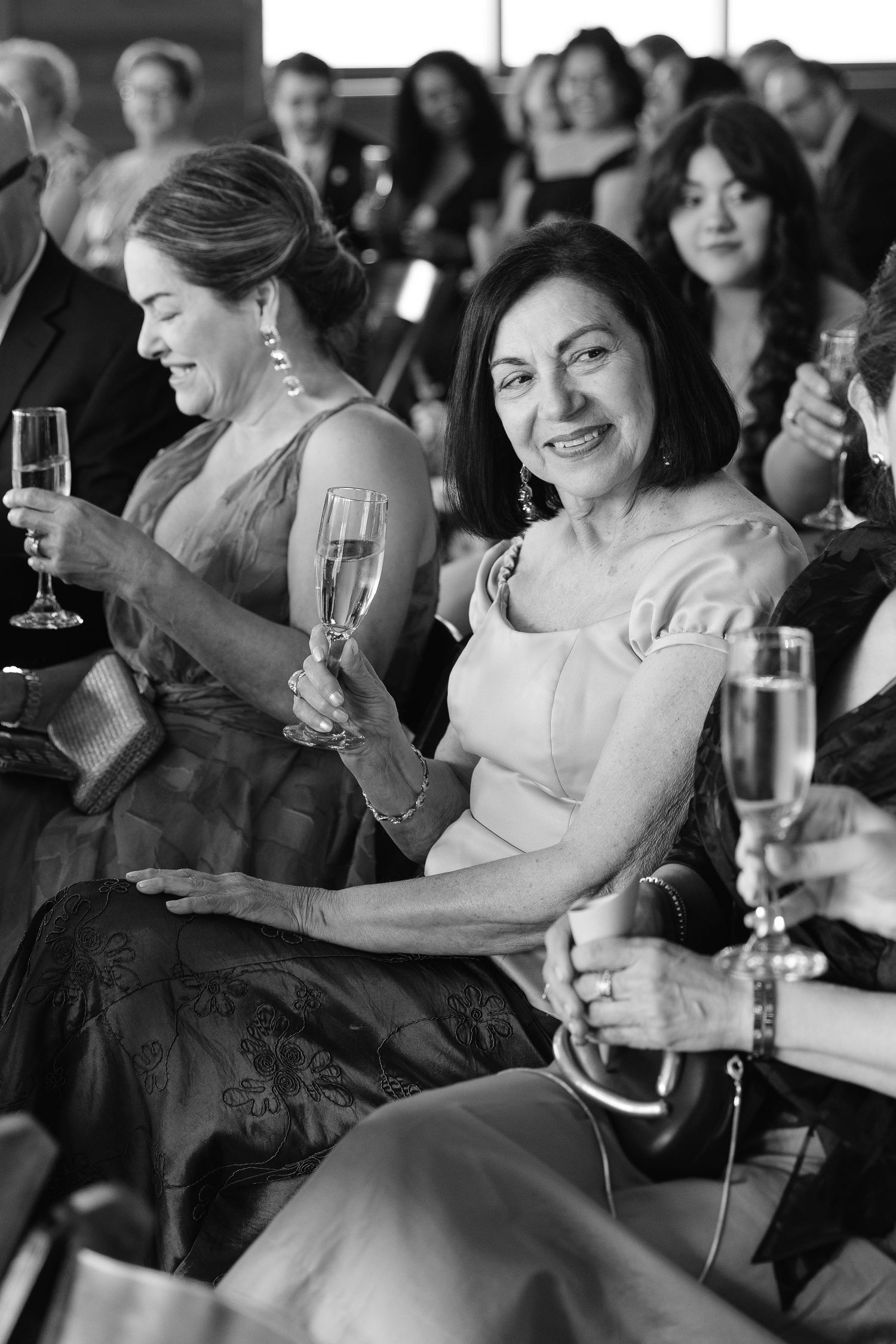 Elegantly dressed guests smile and enjoy champagne at an upscale ceremony in black and white photography in Westfield NC, Mountain Wedding